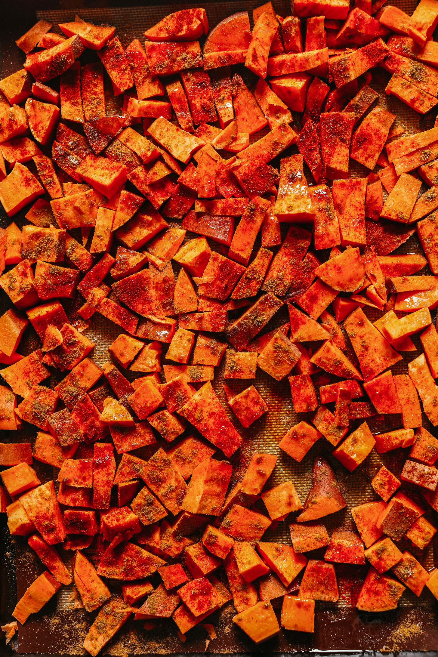 Baking sheet with cumin-spiced cubed sweet potato for making homemade vegan enchiladas
