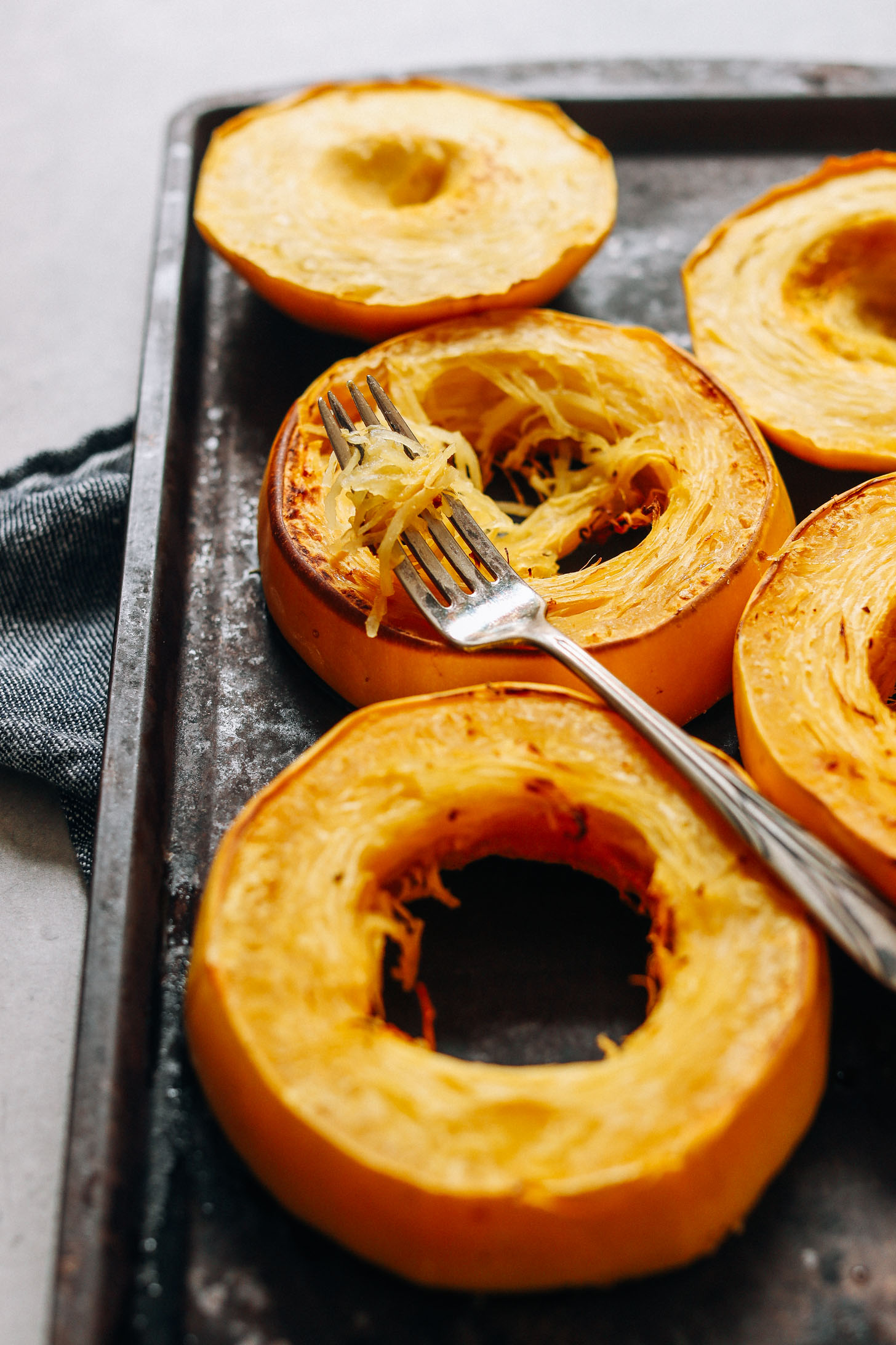 Sliced rounds of freshly baked spaghetti squash on a baking sheet