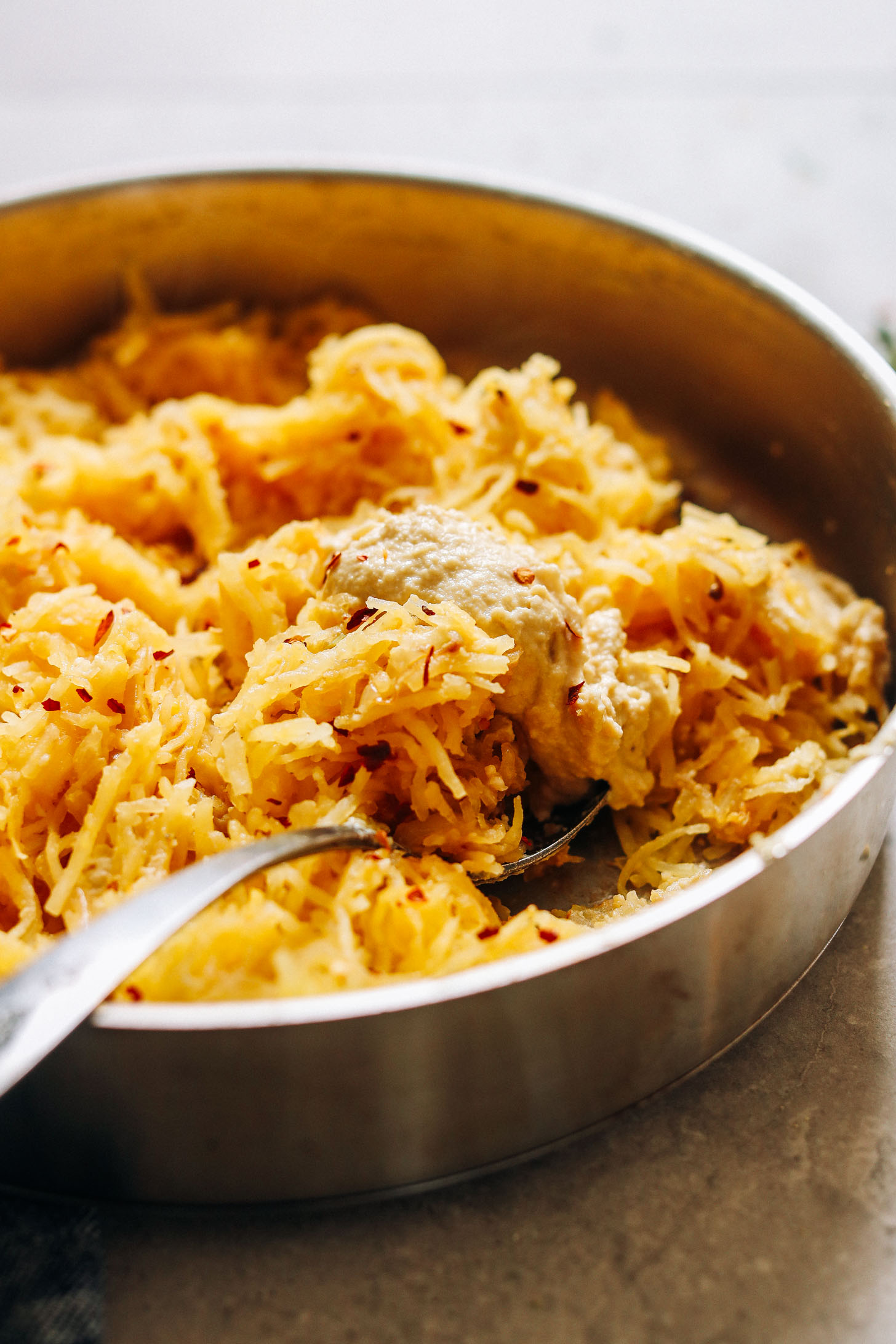 Pan filled with cooked spaghetti squash and vegan cheese sauce