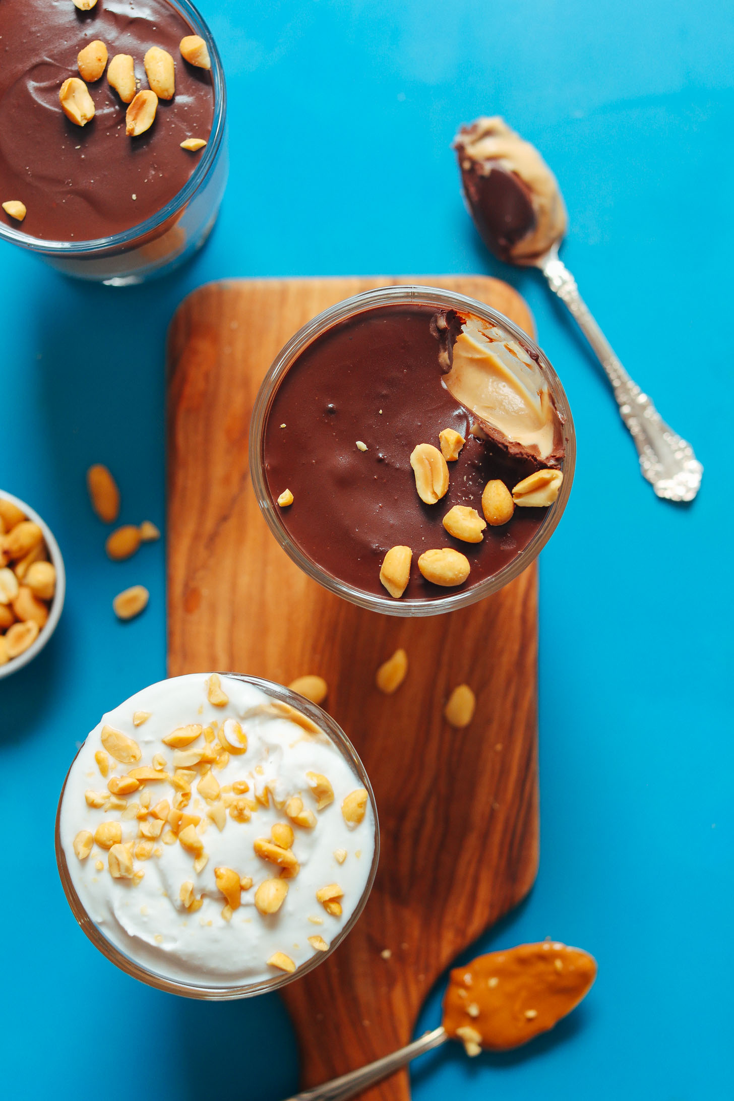 Glasses of Vegan Peanut Butter Pudding topped with chocolate ganache or coconut whip