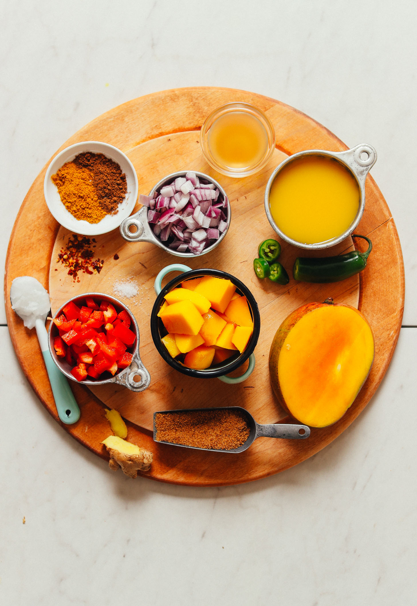 Wood cutting board filled with ingredients for making vegan Spicy Mango Chutney