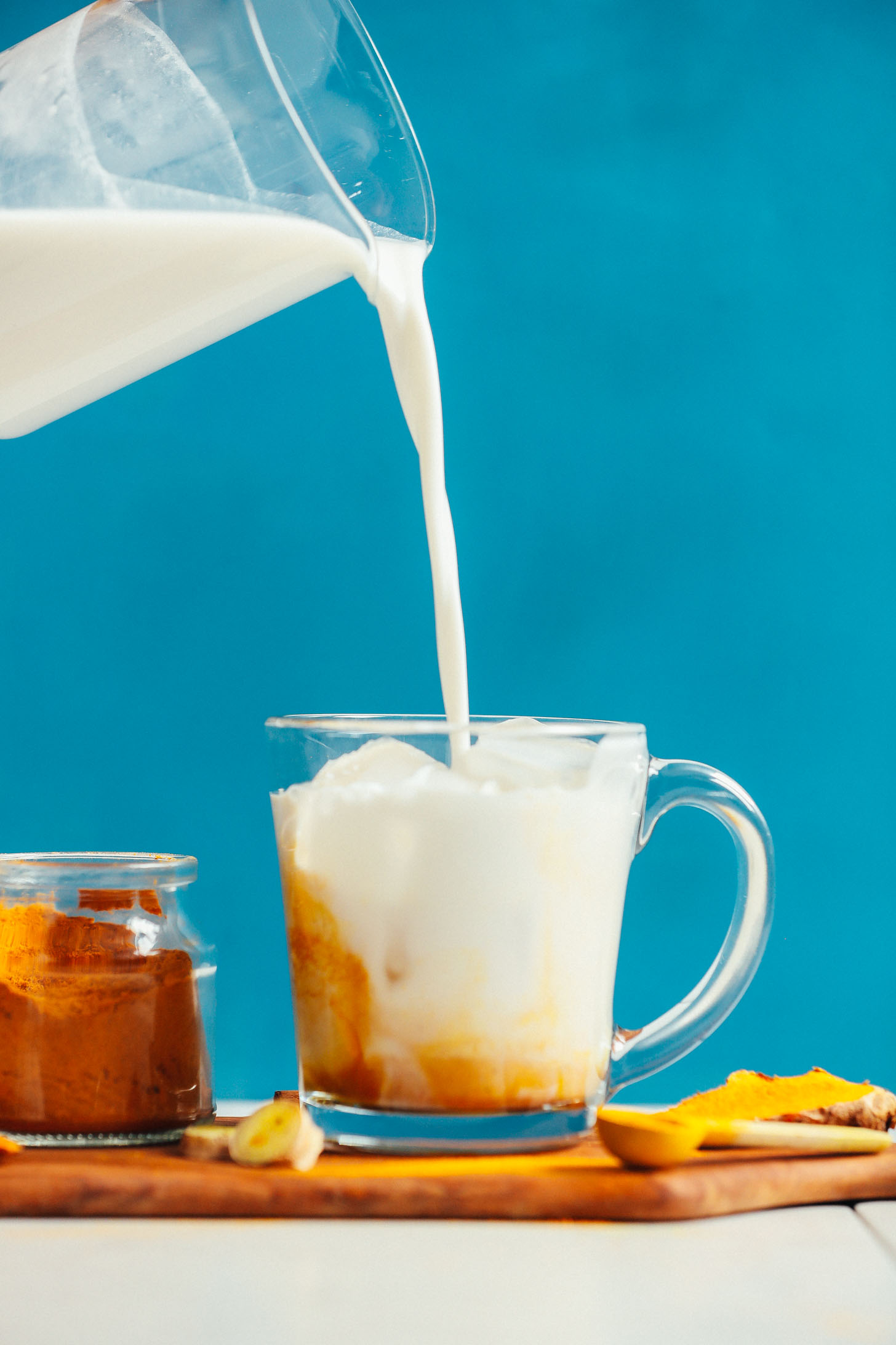 Pouring coconut milk into a mug filled with our homemade golden milk mix