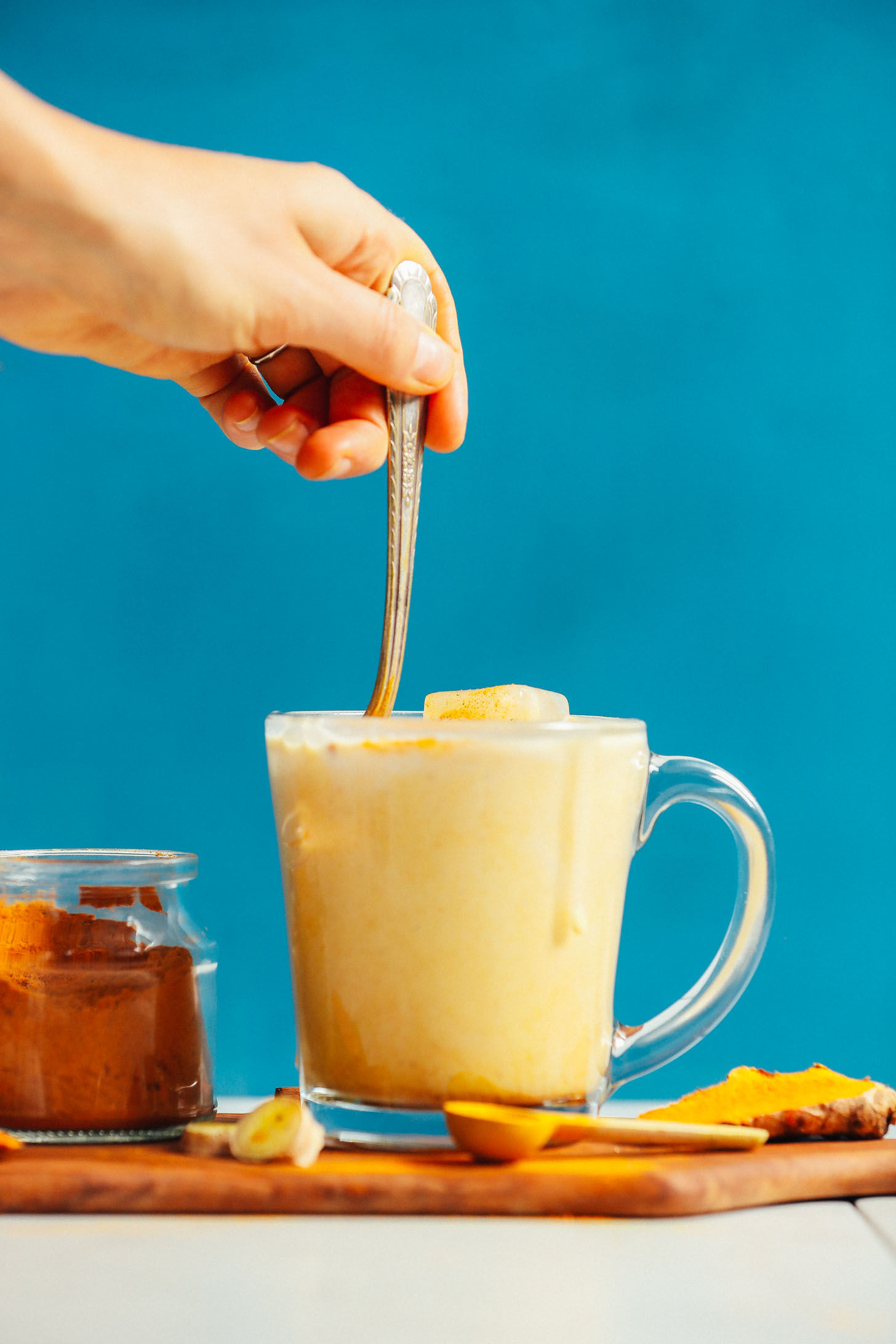 Stirring a glass mug of delicious vegan iced golden milk