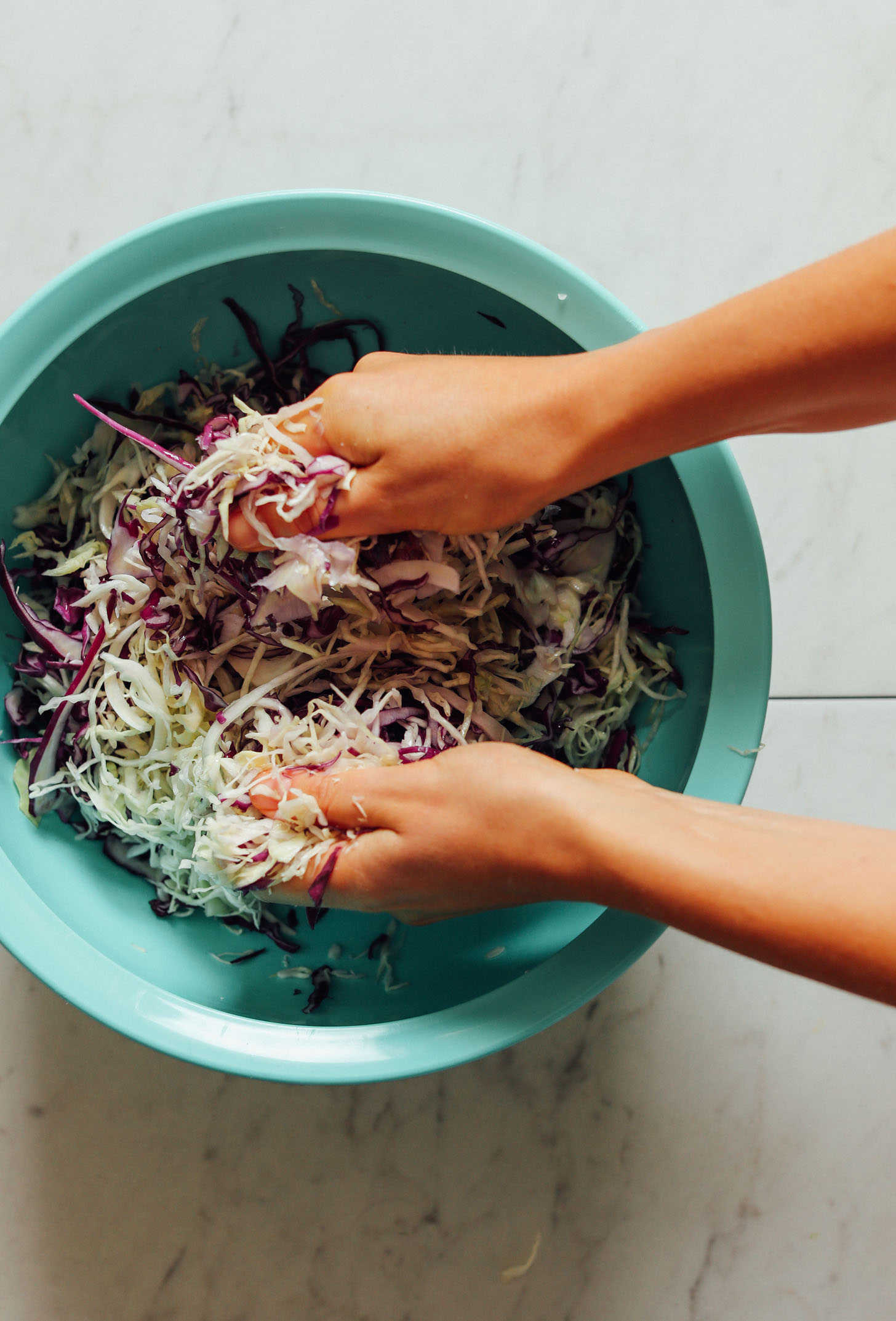 Massaging red and green cabbage to release moisture