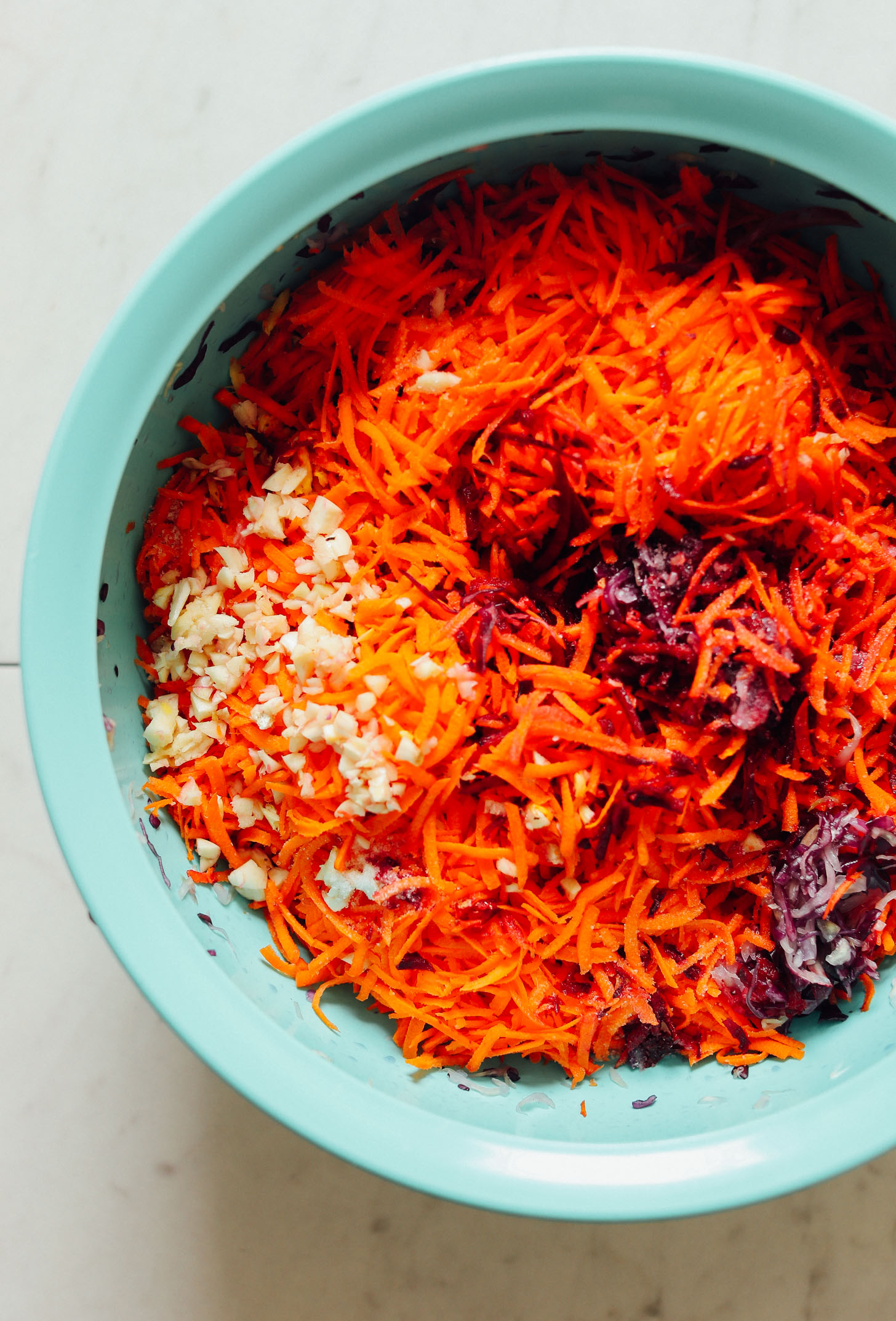 Big bowl of massaged cabbage, shredded carrots, and chopped garlic