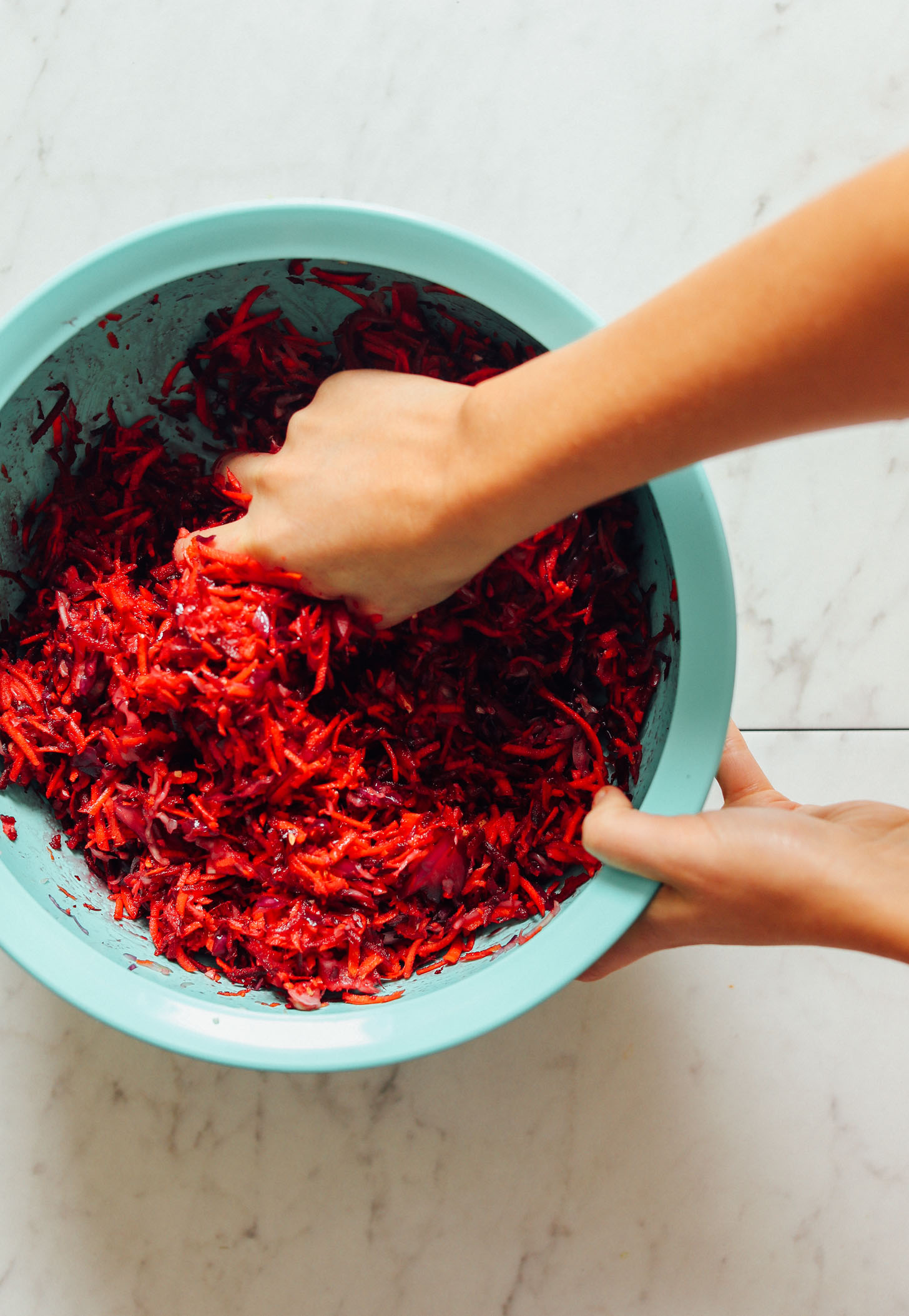 Massaging beets, carrots, and cabbage for our tutorial on How to Make Sauerkraut