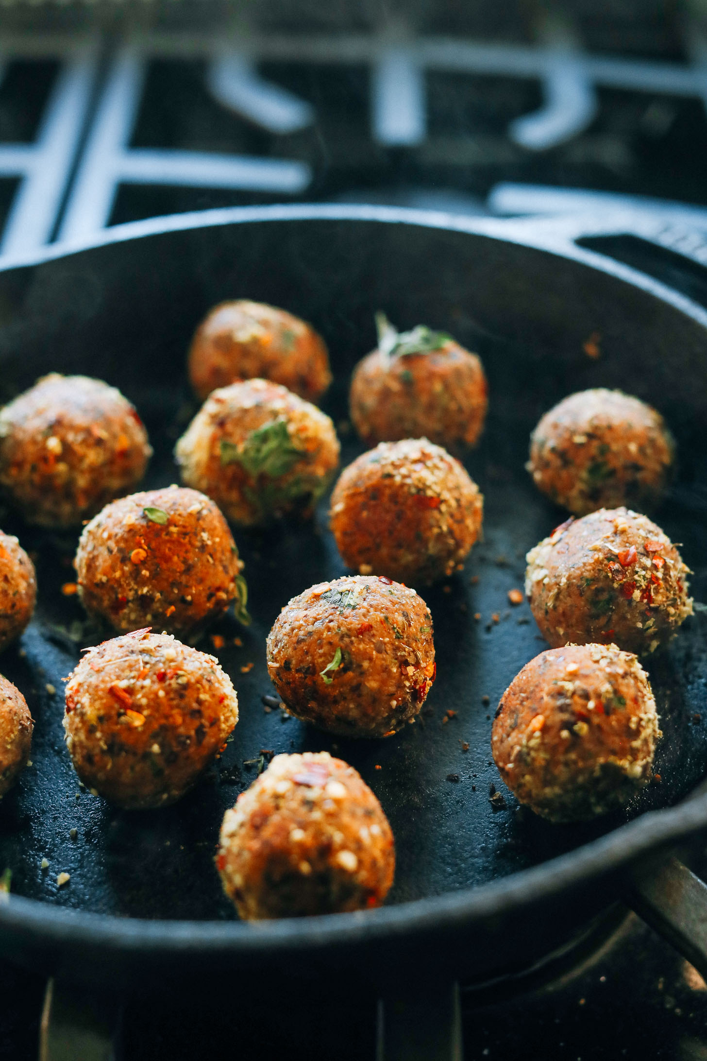 Browning vegan meatballs in a cast-iron skillet
