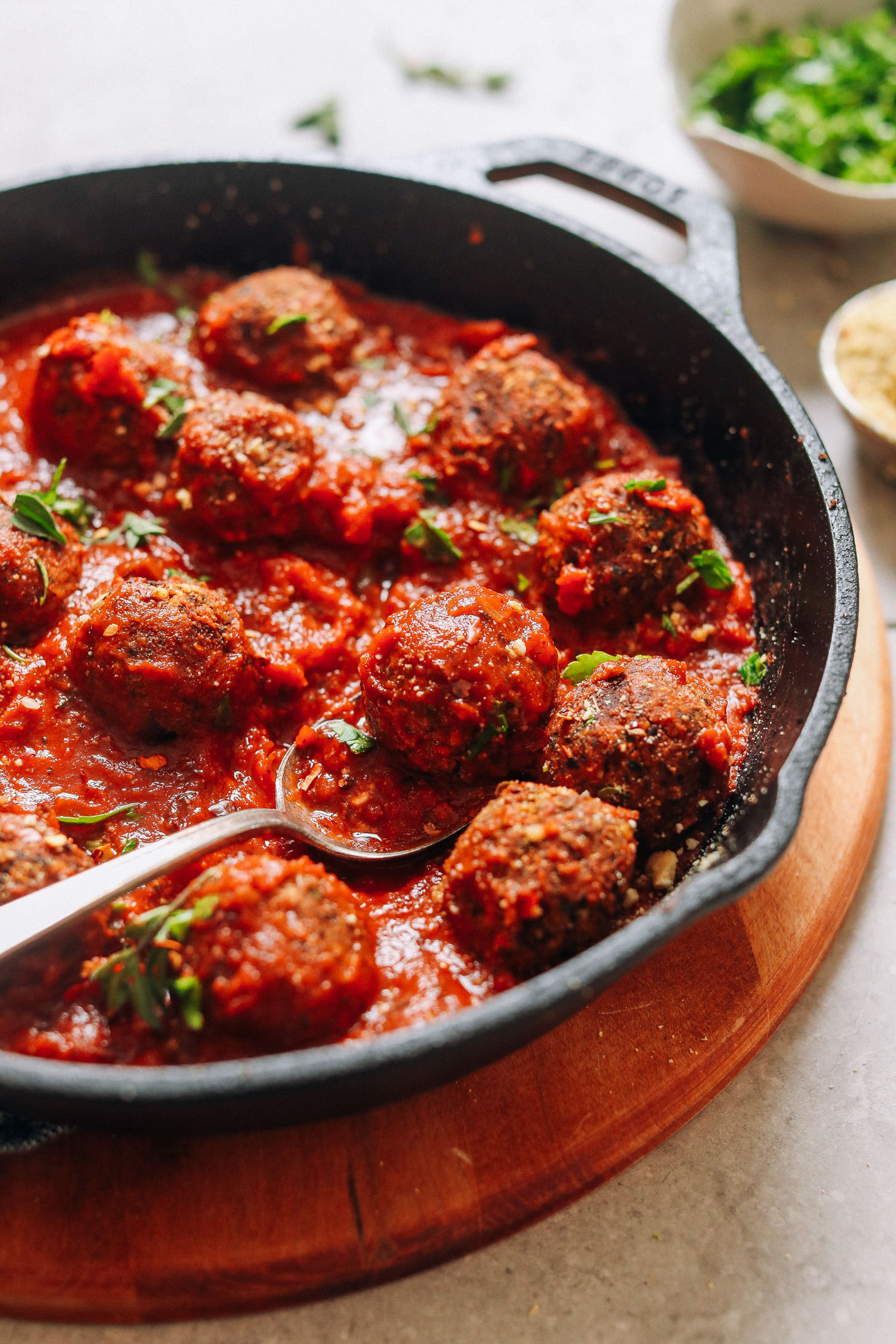 Using a spoon to grab a vegan meatball and marinara sauce