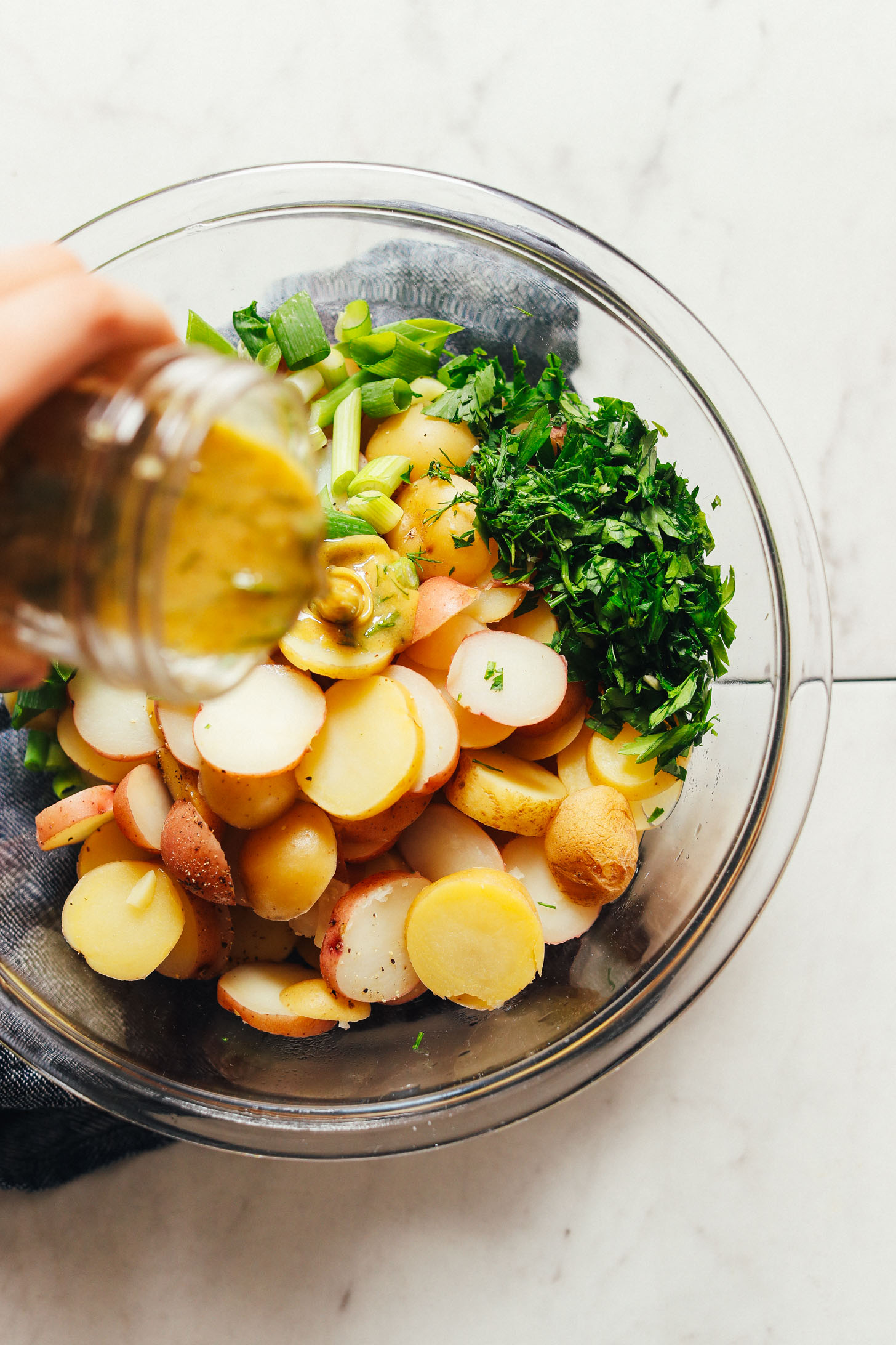 Pouring homemade French Style dressing over potato salad ingredients