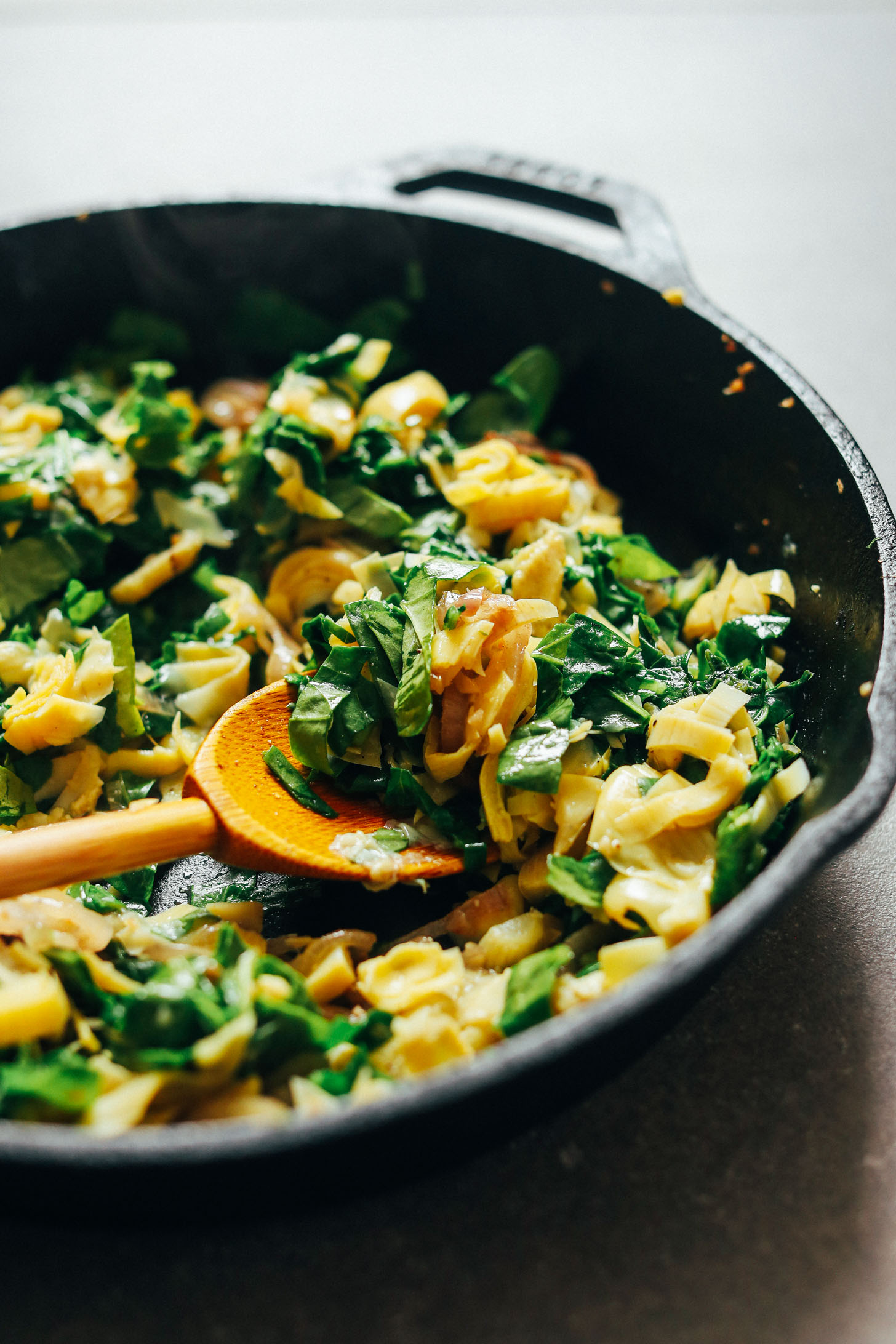Sautéing vegetables in a cast-iron skillet for homemade Vegan GF Spinach and Artichoke Dip