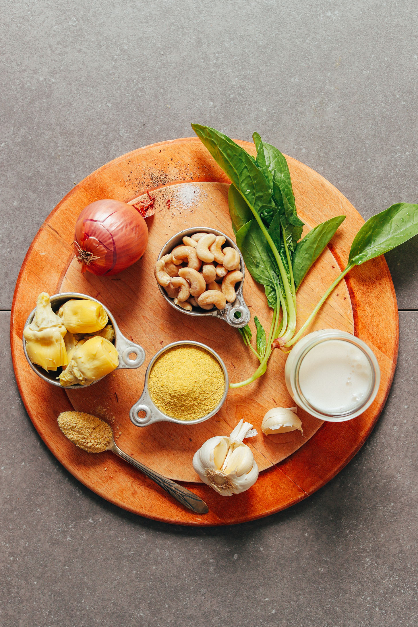 Wood cutting board displaying ingredients for making our vegan Spinach Artichoke Dip recipe