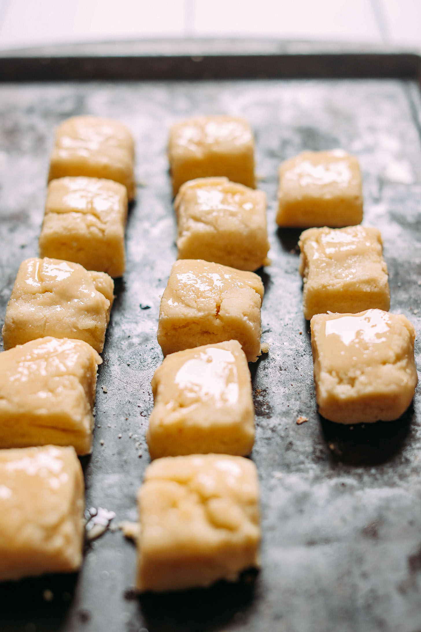 Baking sheet with biscuits brushed with vegan butter ready for baking