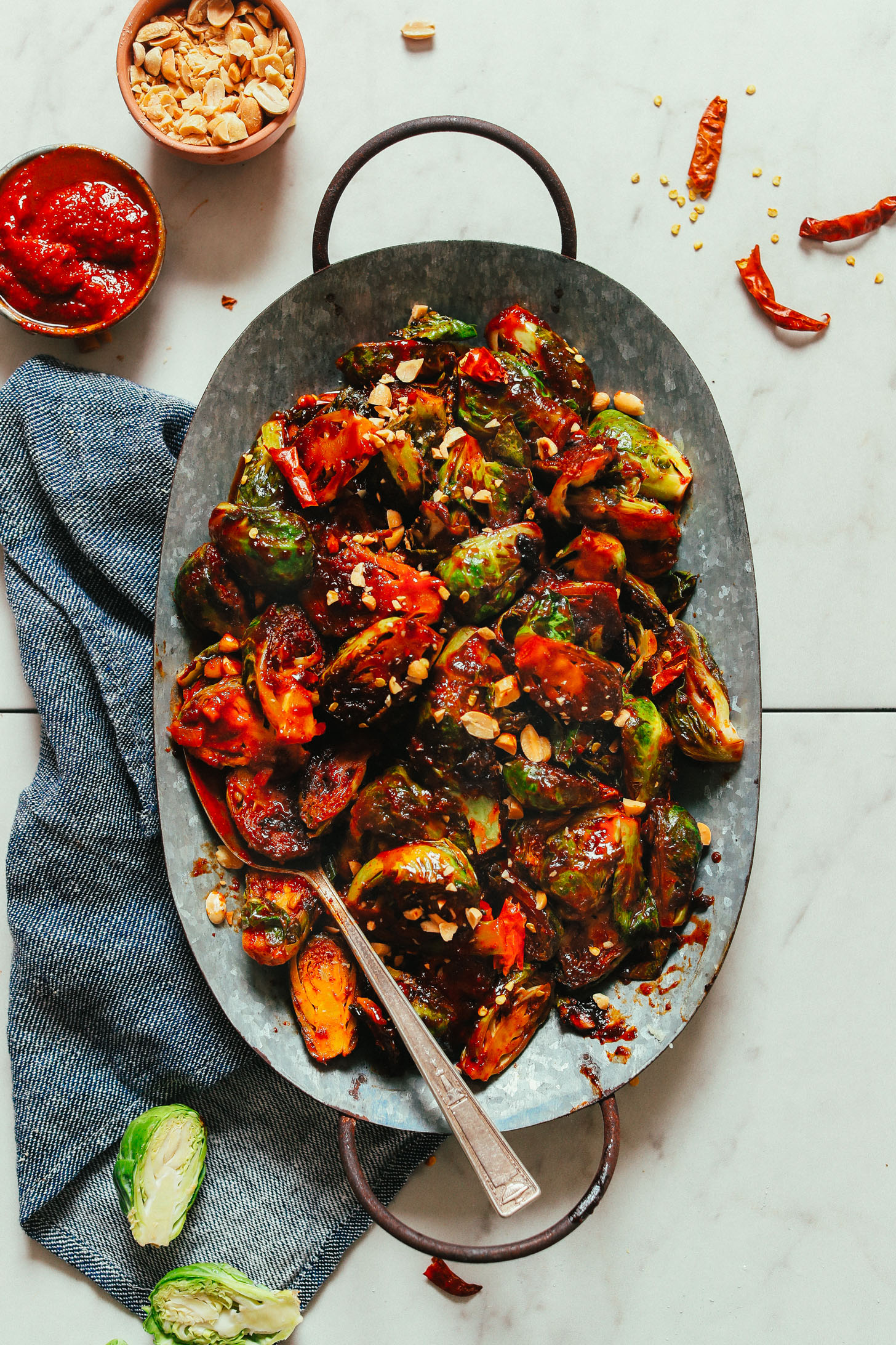 Platter of spicy vegan Gochujang Brussels Sprouts topped with peanuts