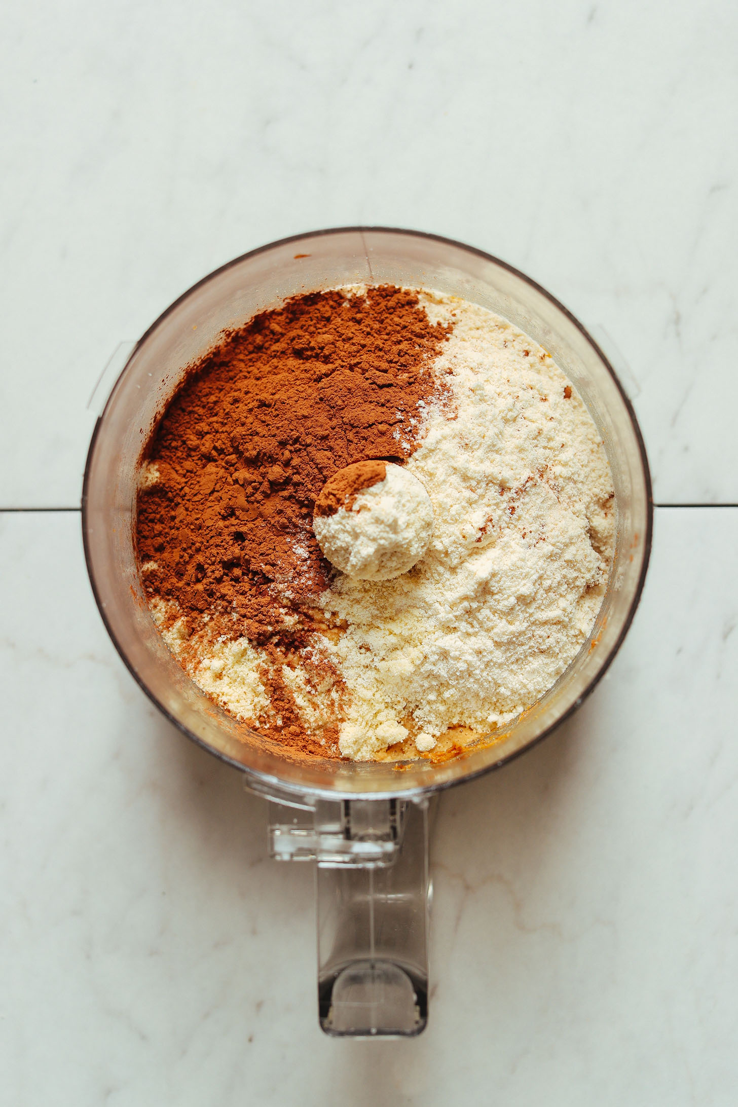 Food processor filled with ingredients for making gluten-free Vegan Chocolate Cake Bites