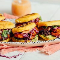 Tray of Vegan Arepa Sandwiches with a jar of hot sauce in the background