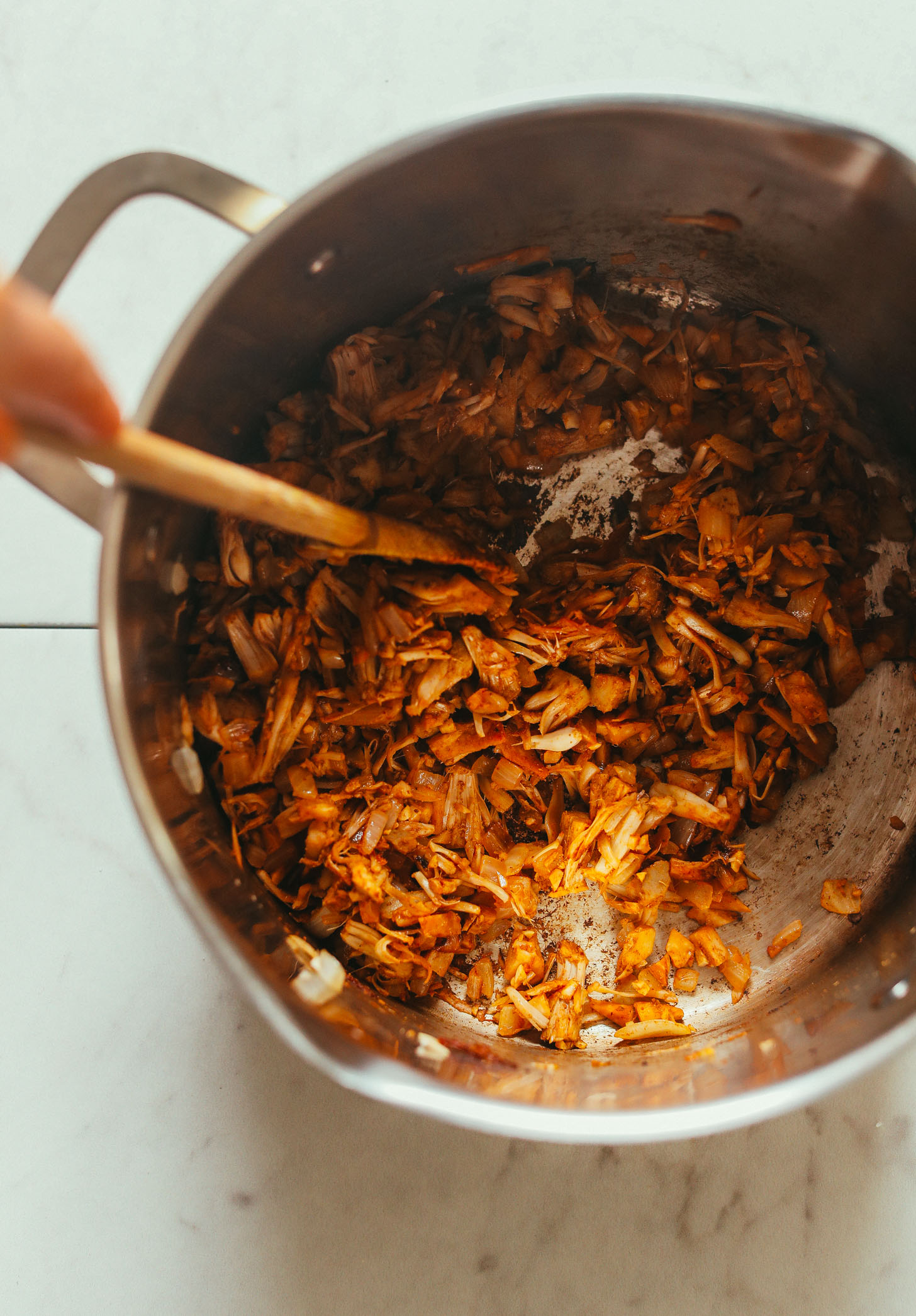 Using a wooden spoon to stir jackfruit and spices