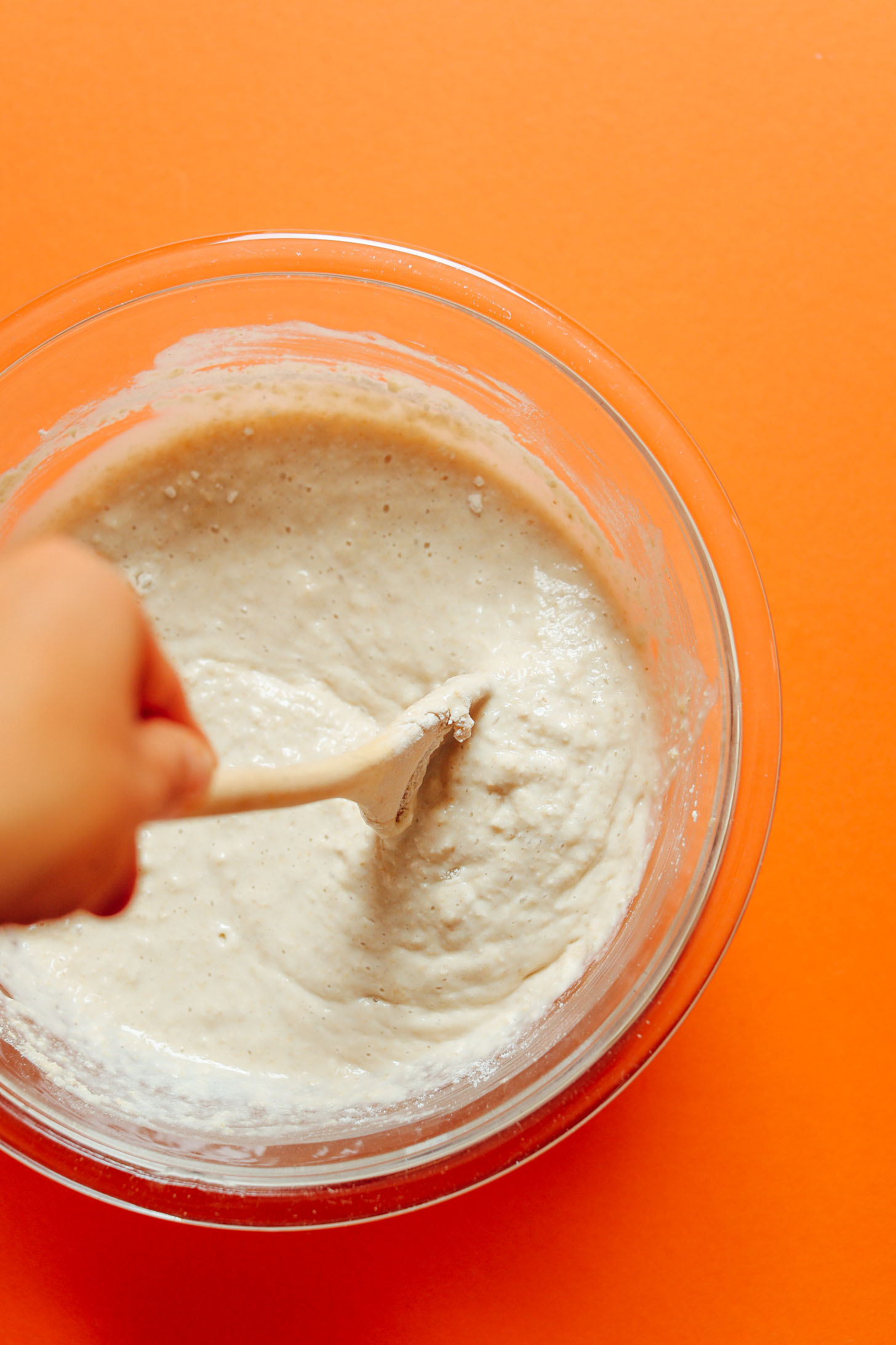Using a wooden spoon to stir together ingredients for Banana Oat Pancakes