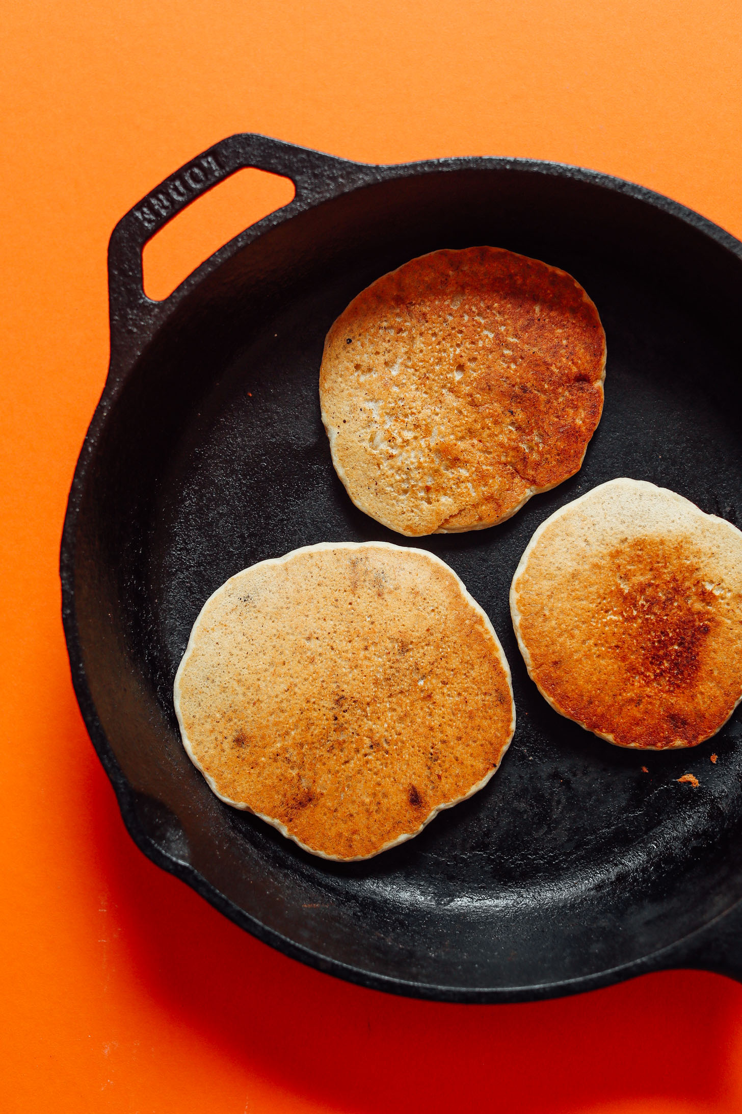 Cooking gluten-free vegan Banana Oat Pancakes in a skillet
