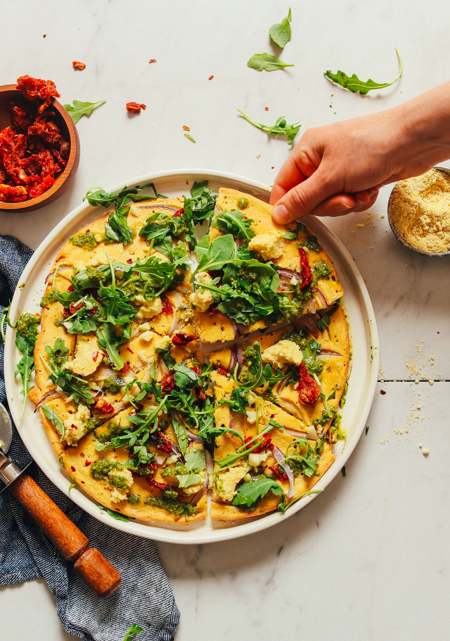 Grabbing a slice of our homemade Socca Pizza with Vegan Pesto recipe