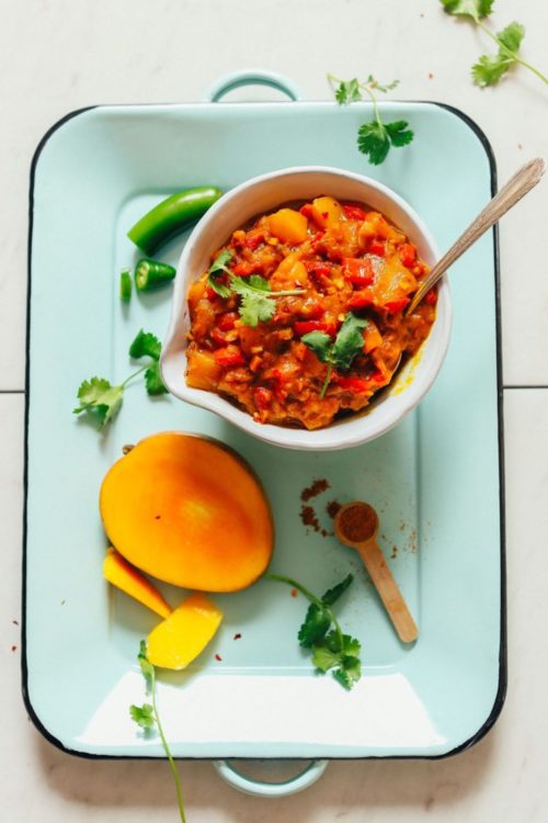 Bowl of Spicy Mango Chutney on a platter with ingredients used to make the recipe