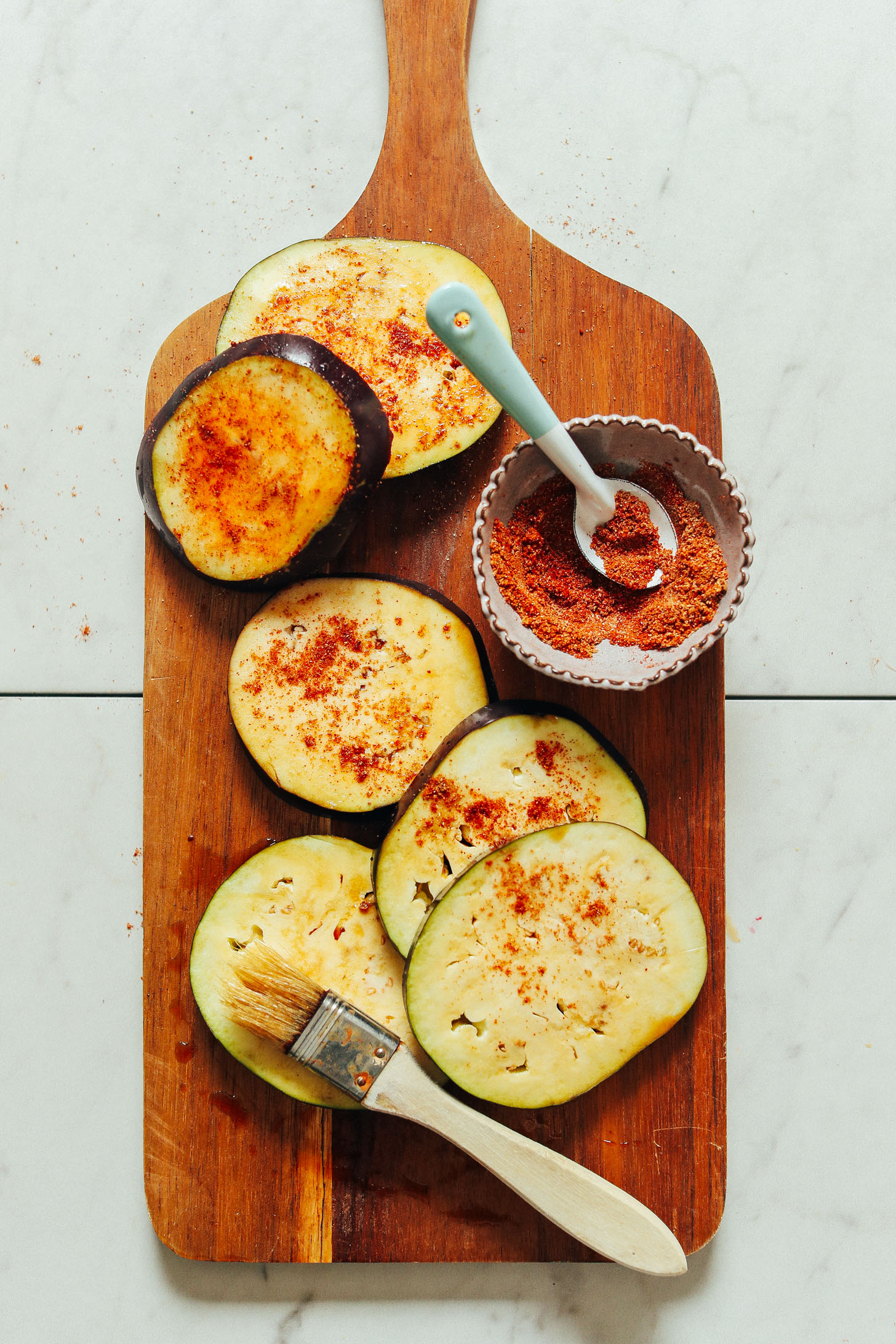 An overhead shot of sliced eggplant seasoned with spice blend rubbed on.