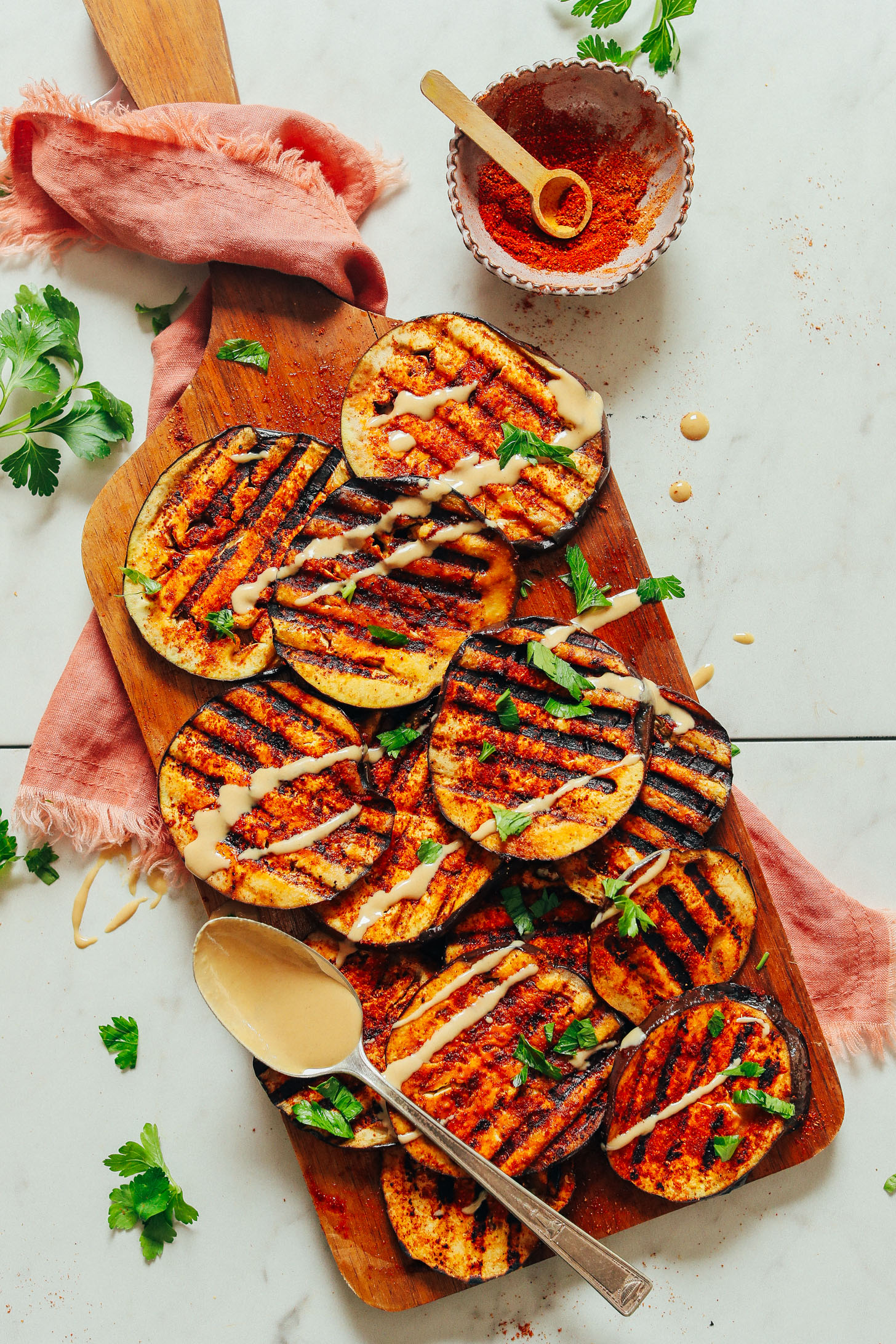 An overhead shot of simple grilled eggplant slices drizzled with tahini dressing and spice blend.