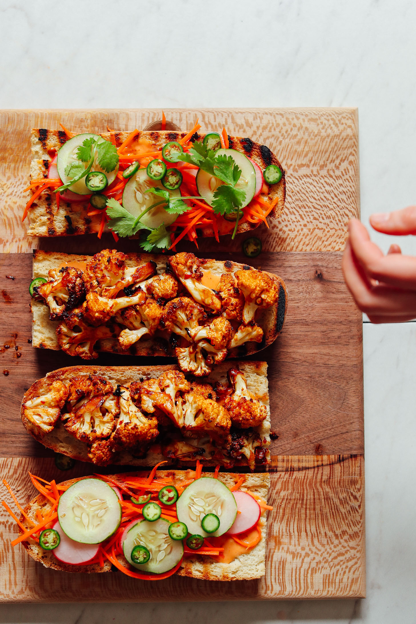 Open-faced Cauliflower Banh Mi sandwiches resting on a wood cutting board