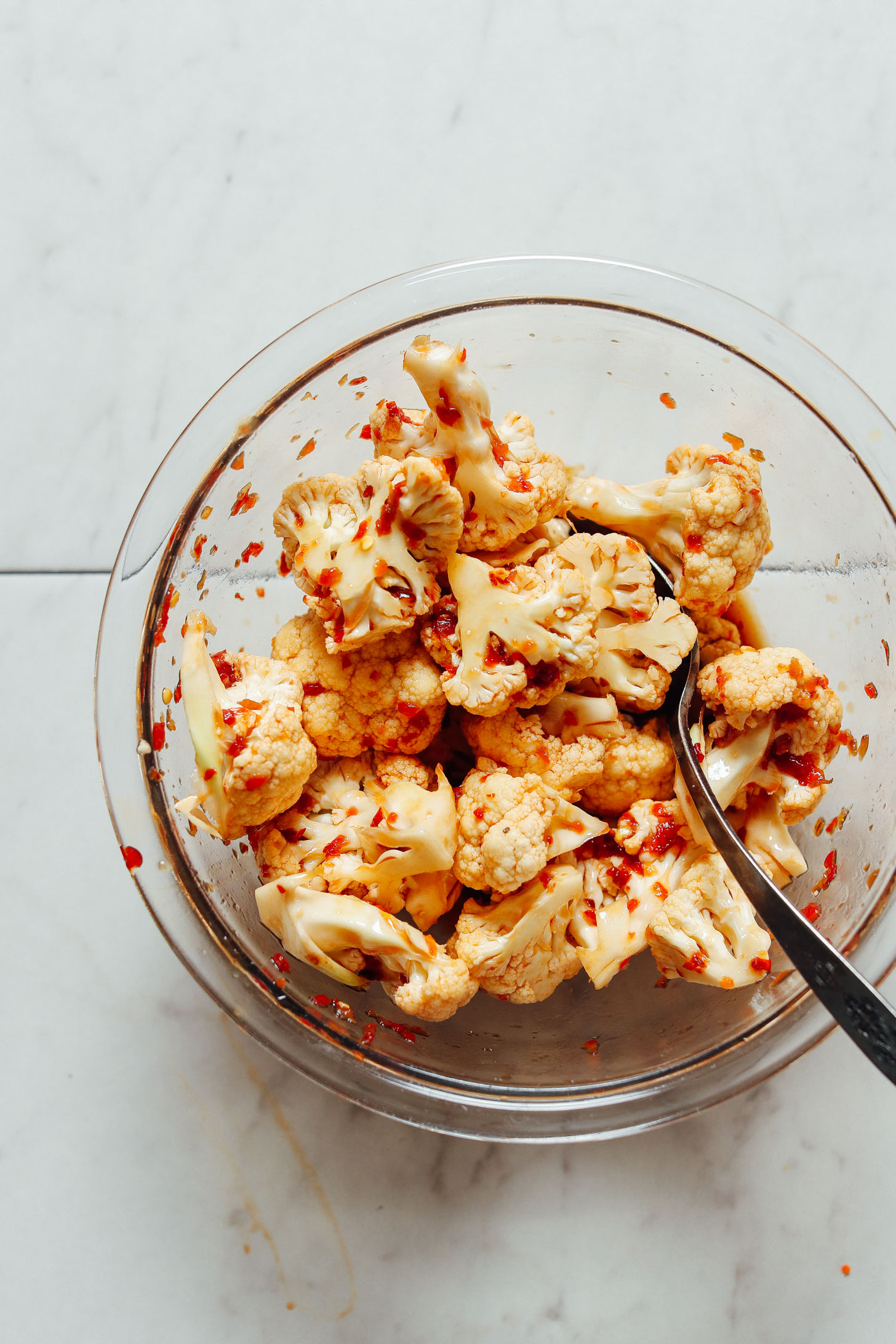 Using a spoon to mix spices with cauliflower for Cauliflower Banh Mi