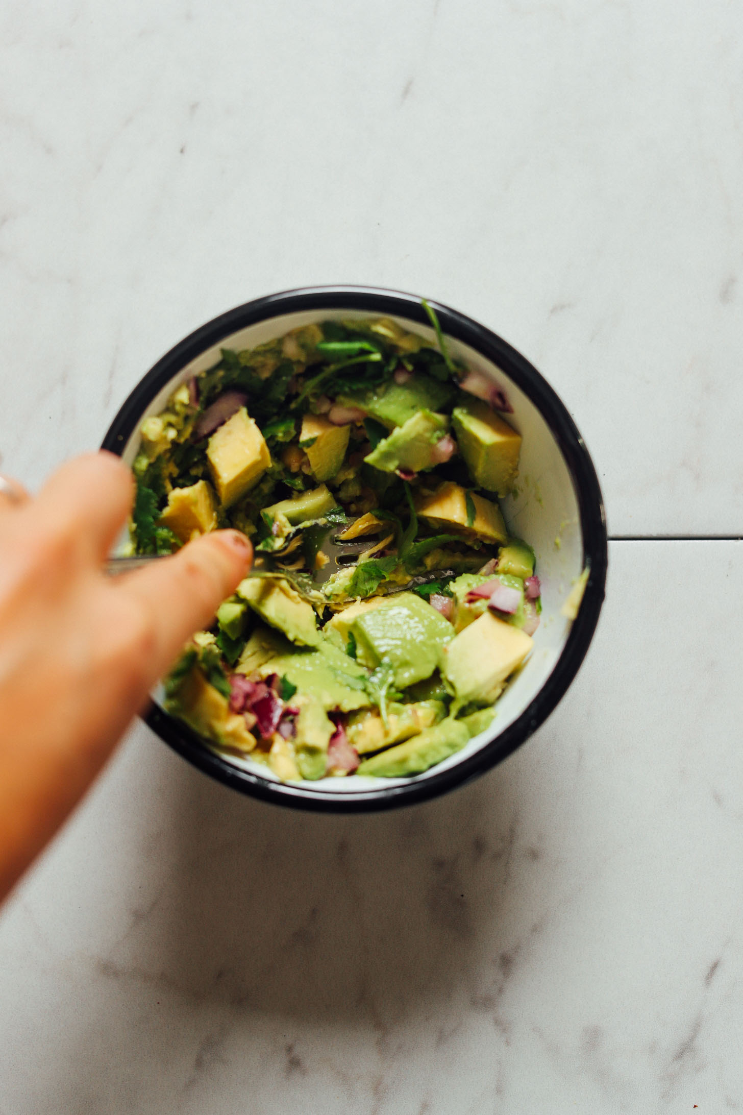 Using a fork to mash avocado for homemade vegan guacamole