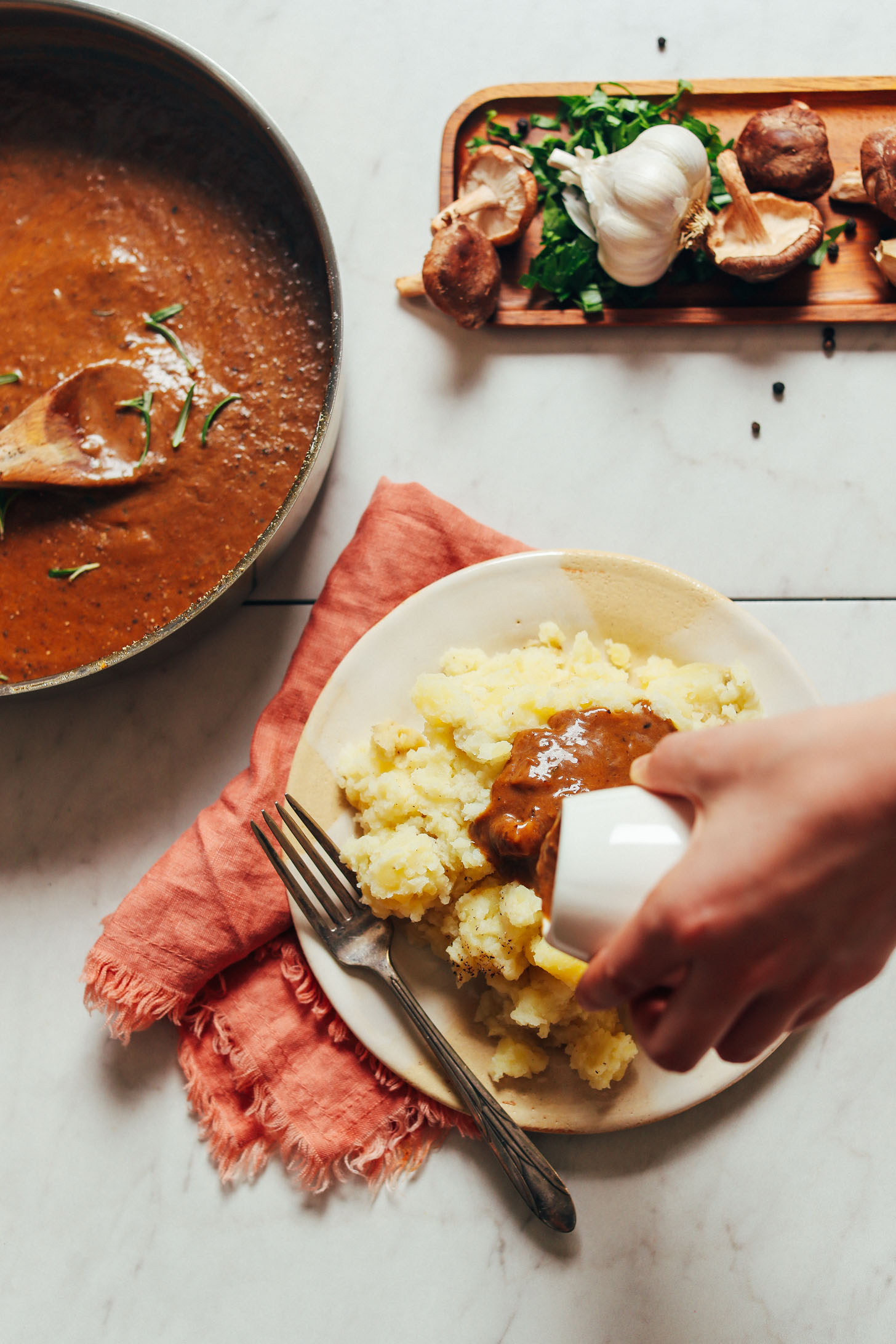 Pouring vegan mushroom gravy over mashed potatoes for Thanksgiving