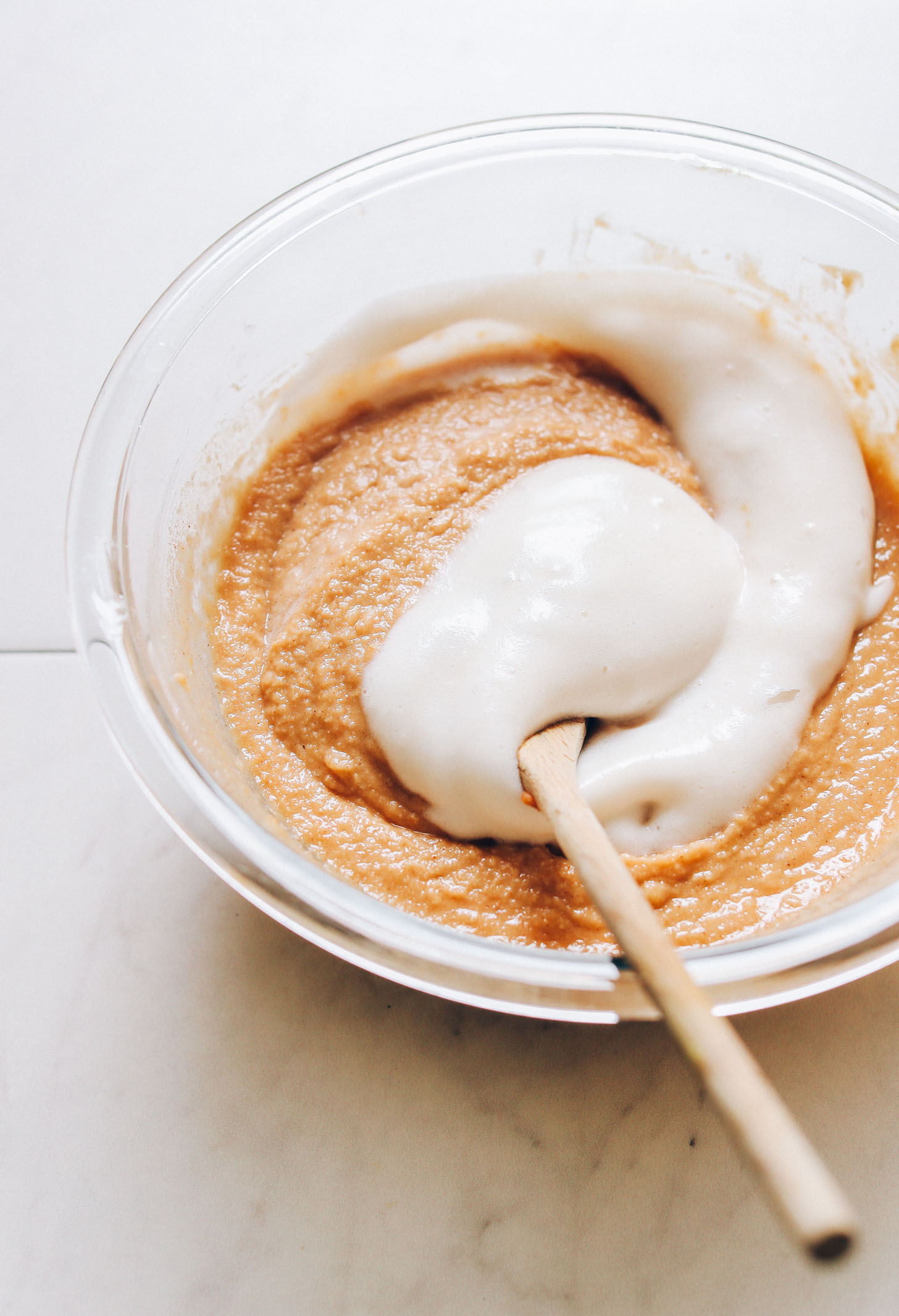 Using a wooden spoon to stir aquafaba into gluten-free vegan donut batter
