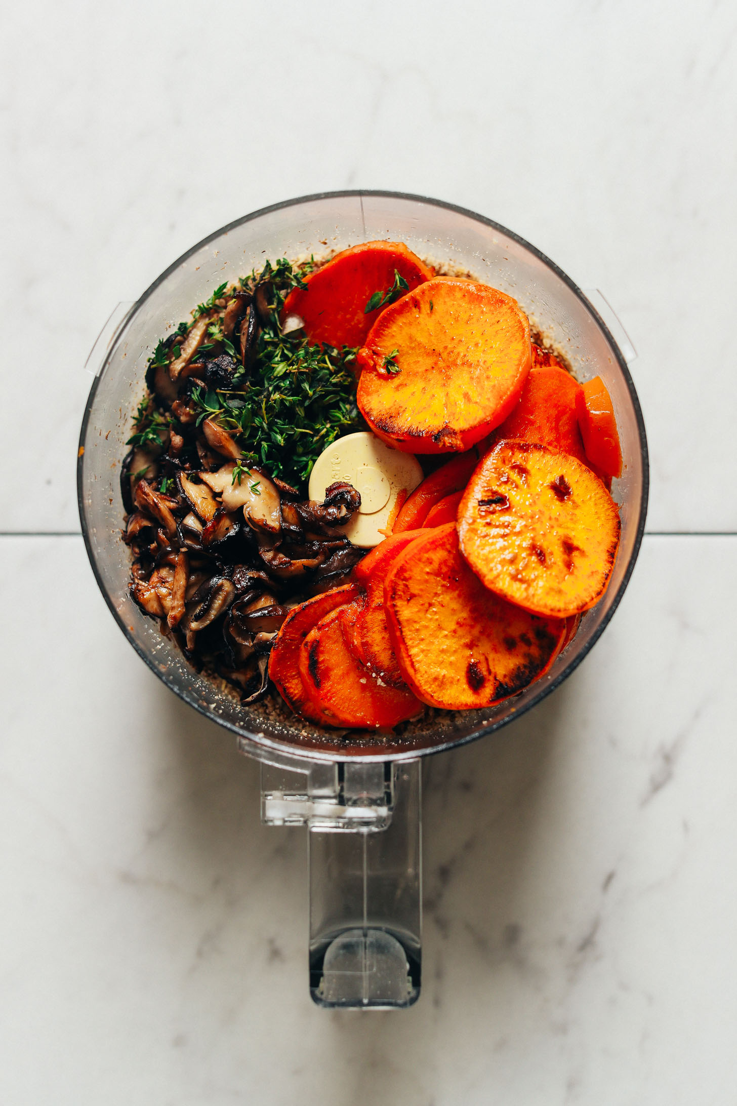 Food processor with mushrooms, sweet potatoes, and other ingredients for making Vegan Holiday Meatloaf