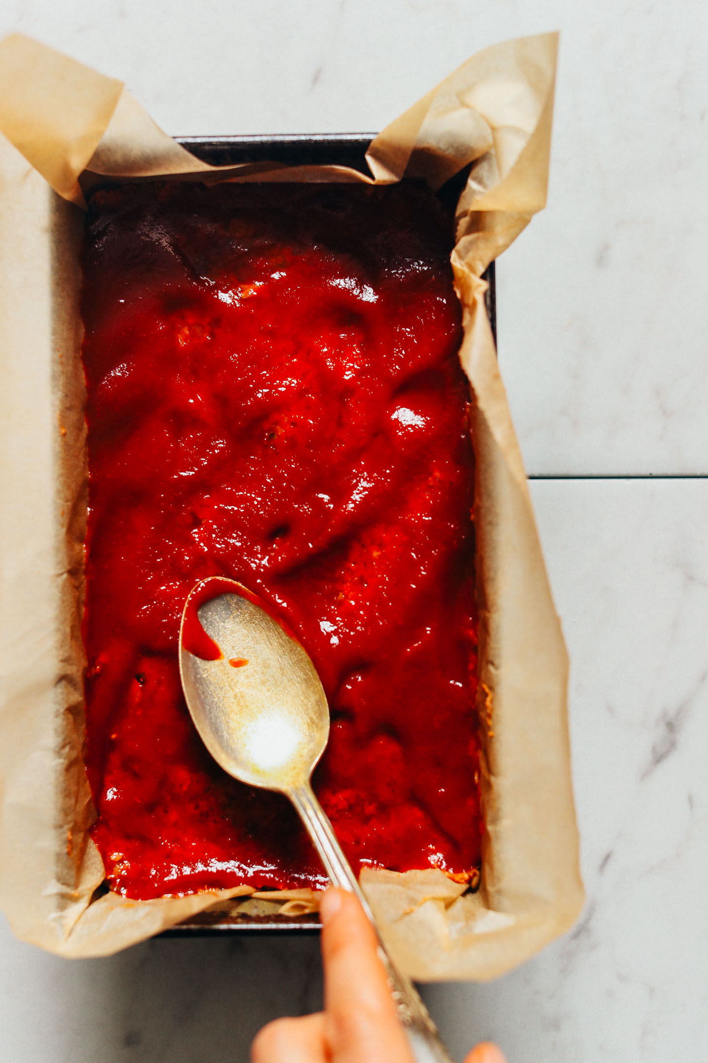Using a spoon to spread glaze over our Vegan Lentil Meatloaf recipe