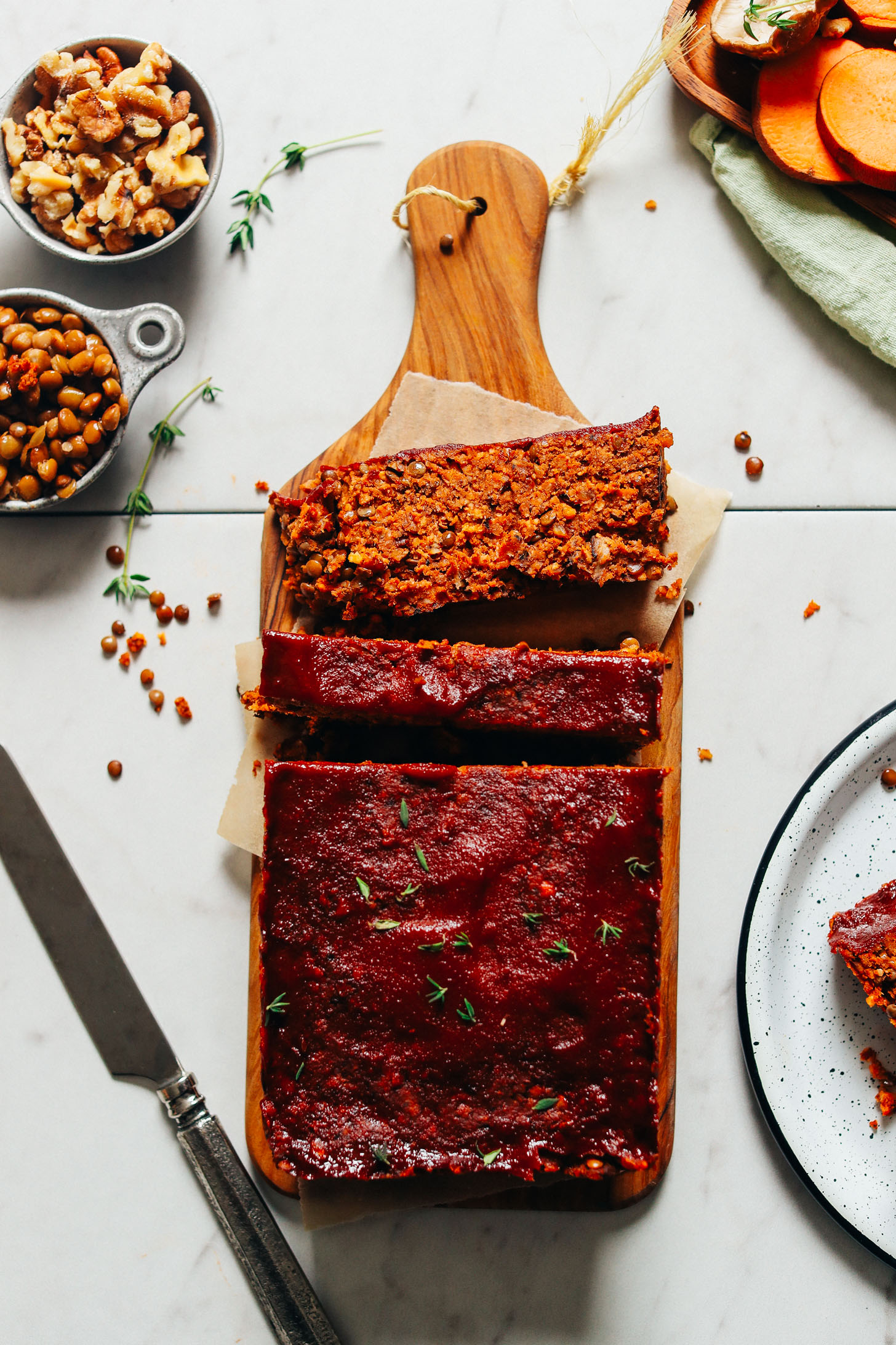 Partially sliced loaf of Vegan Lentil Meatloaf resting on a cutting board