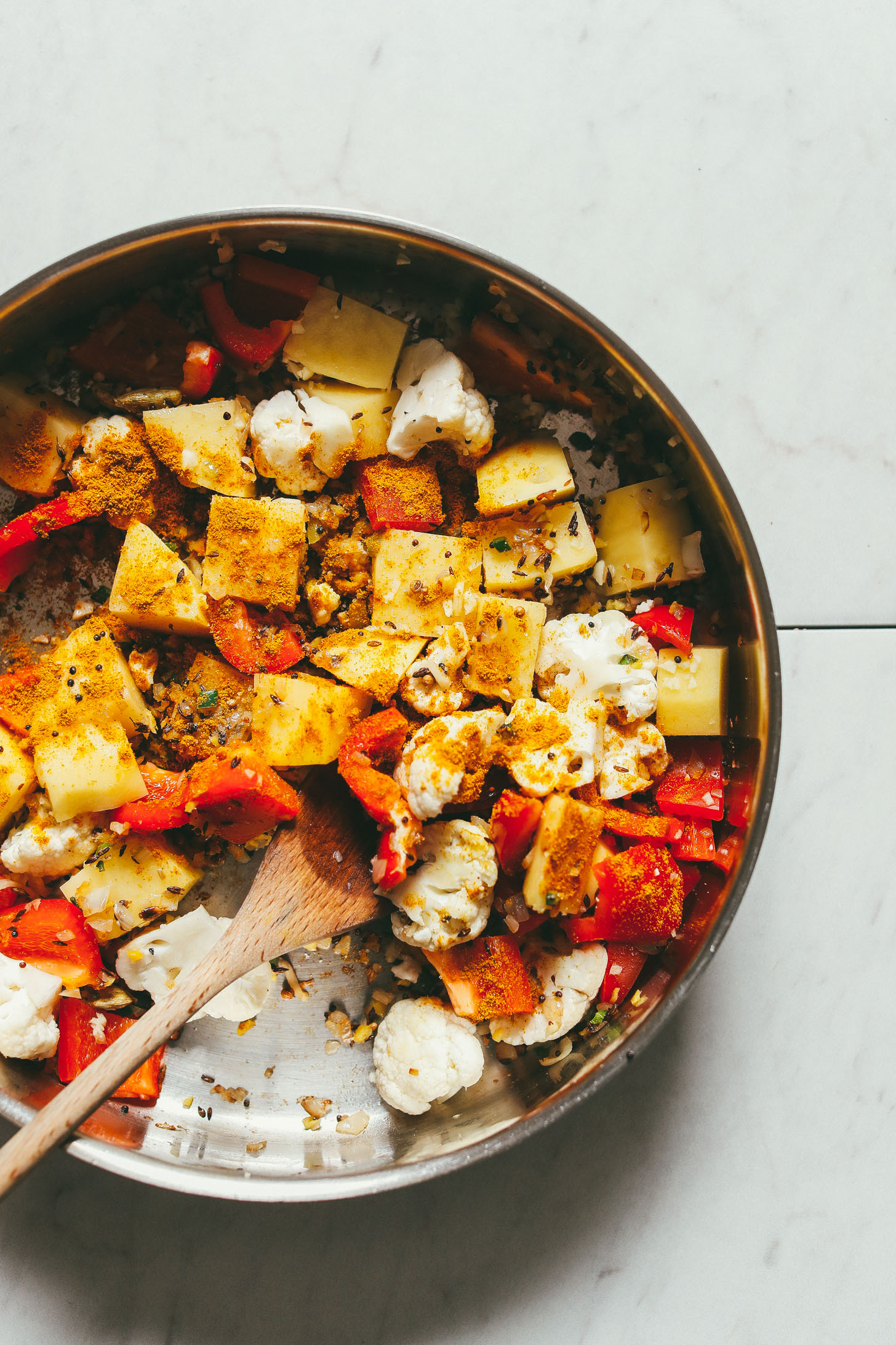 Overhead image of a pan of vegetables being cooked for a red lentil curry
