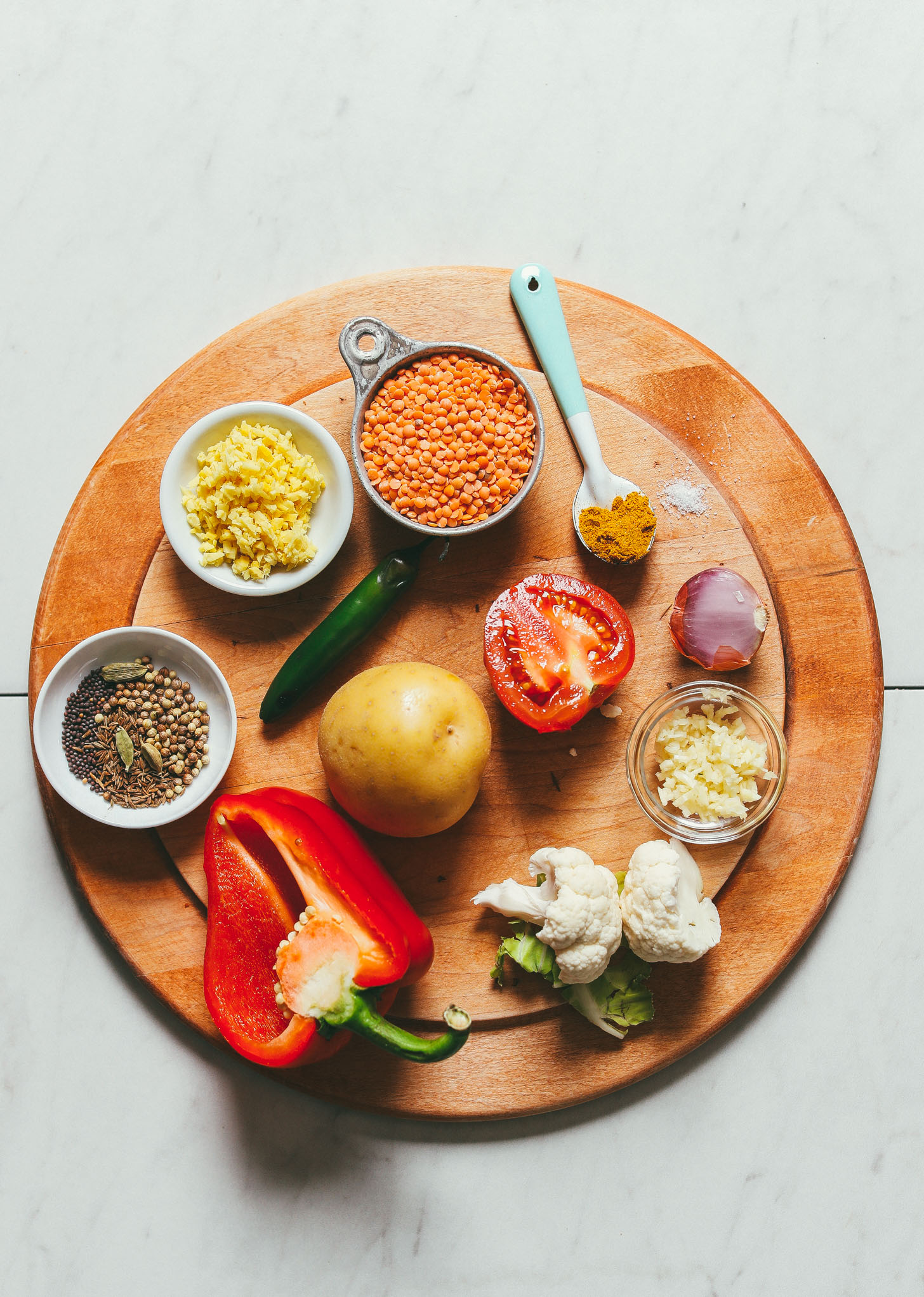 Ingredients for red lentil curry with potato, red bell pepper, and cauliflower on a cutting board