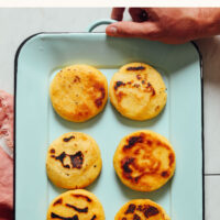 Hands holding a platter of homemade Venezuelan-inspired arepas