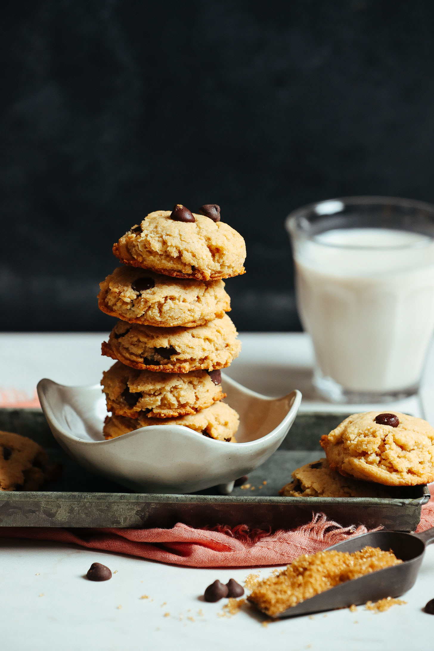 Stack of delicious gluten-free vegan chocolate chip cookies beside a glass of almond milk