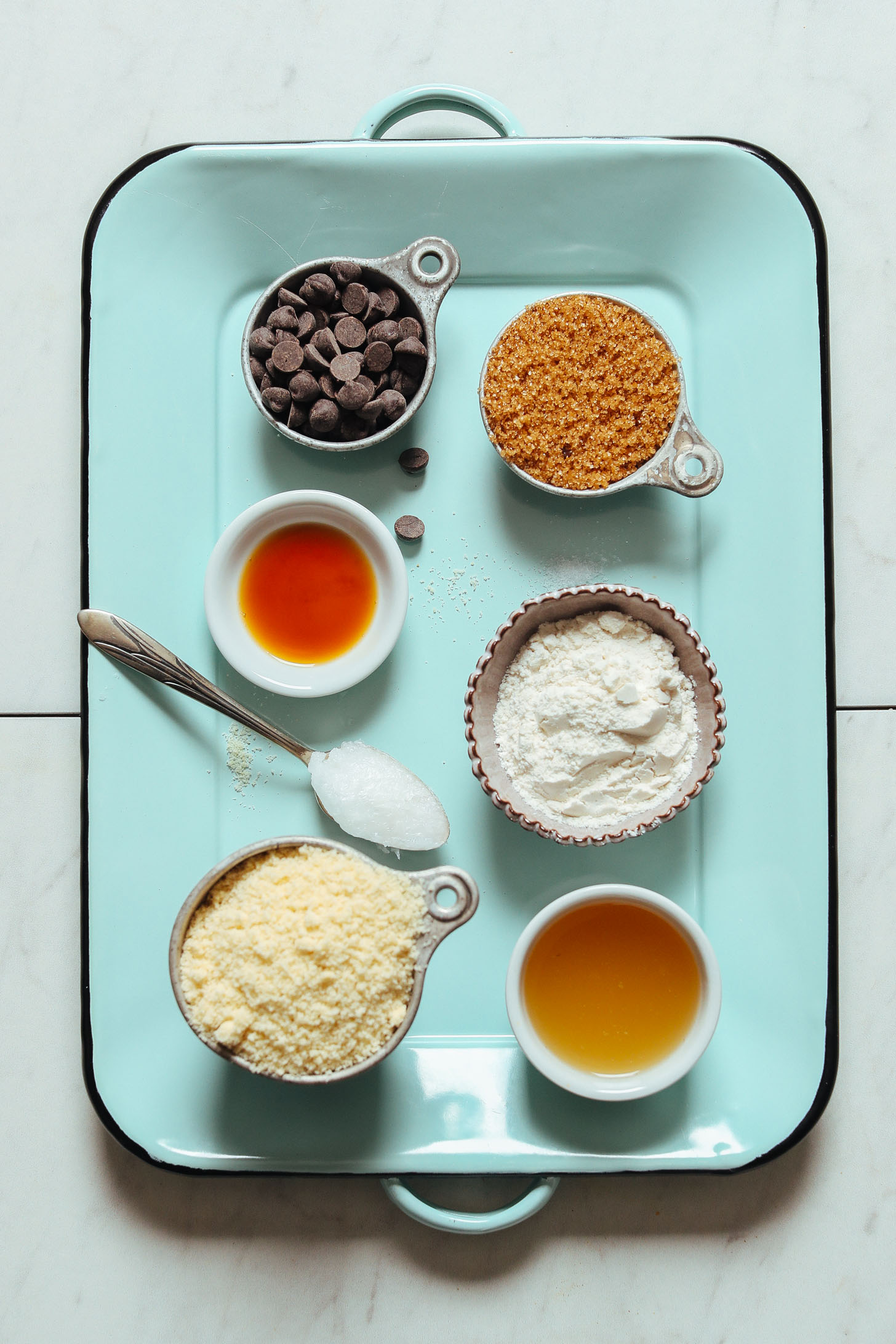 Blue tray displaying almond flour and other ingredients for making vegan gluten-free chocolate chip cookies