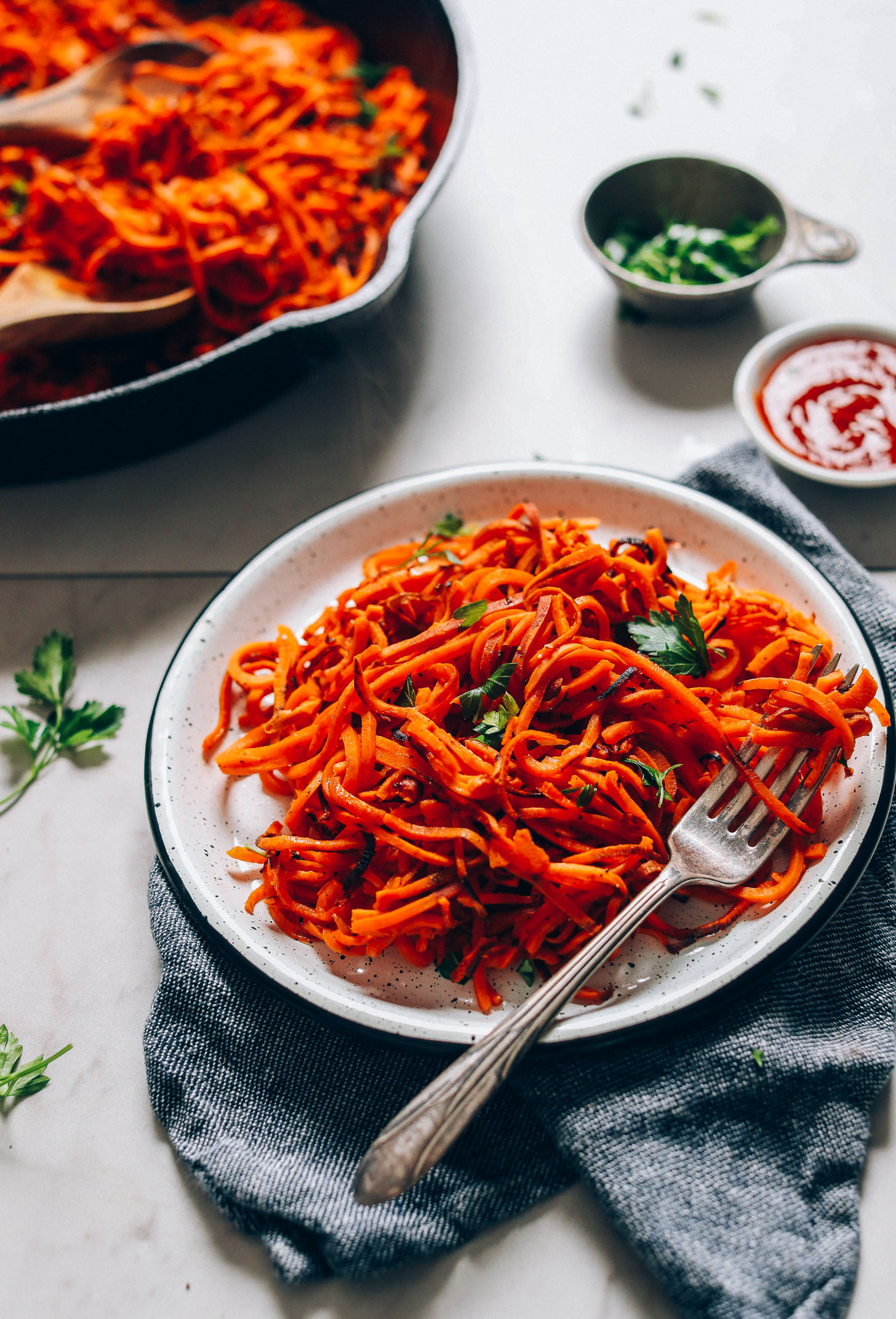 Plate and skillet of our Sweet Potato Hashbrowns recipe alongside parsley and ketchup for serving