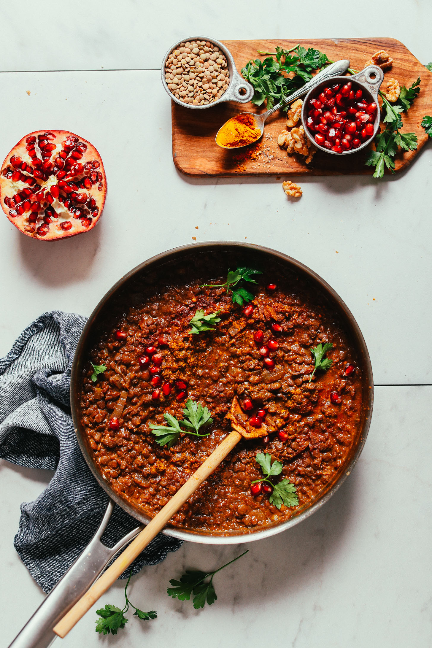 Pan of gluten-free vegan Lentil Fesenjan and a cutting board with ingredients used to make it