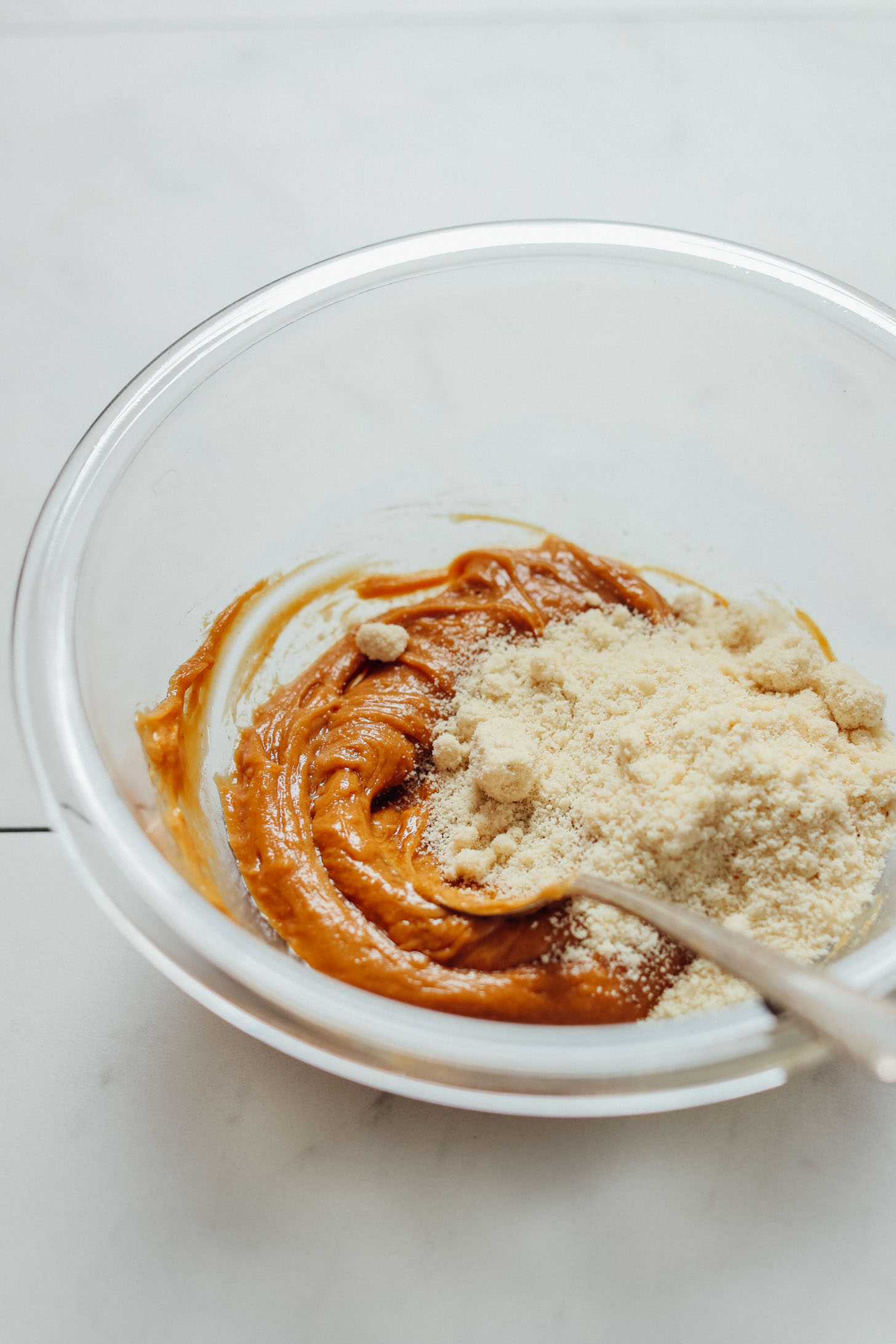 Stirring together peanut butter and almond flour to make homemade Thumbprint Cookies