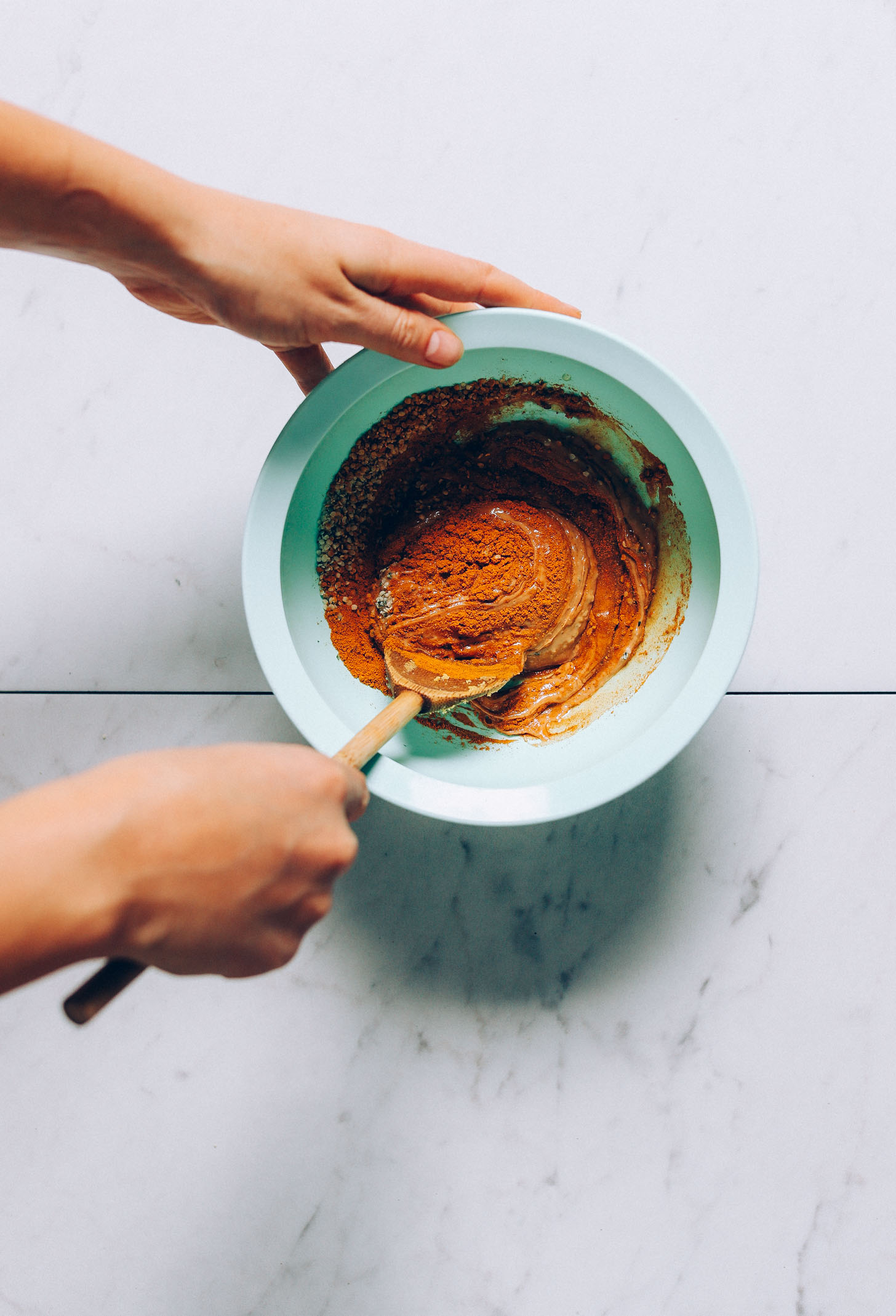 An overhead image of cashew butter being mixed into golden milk spices and maple syrup