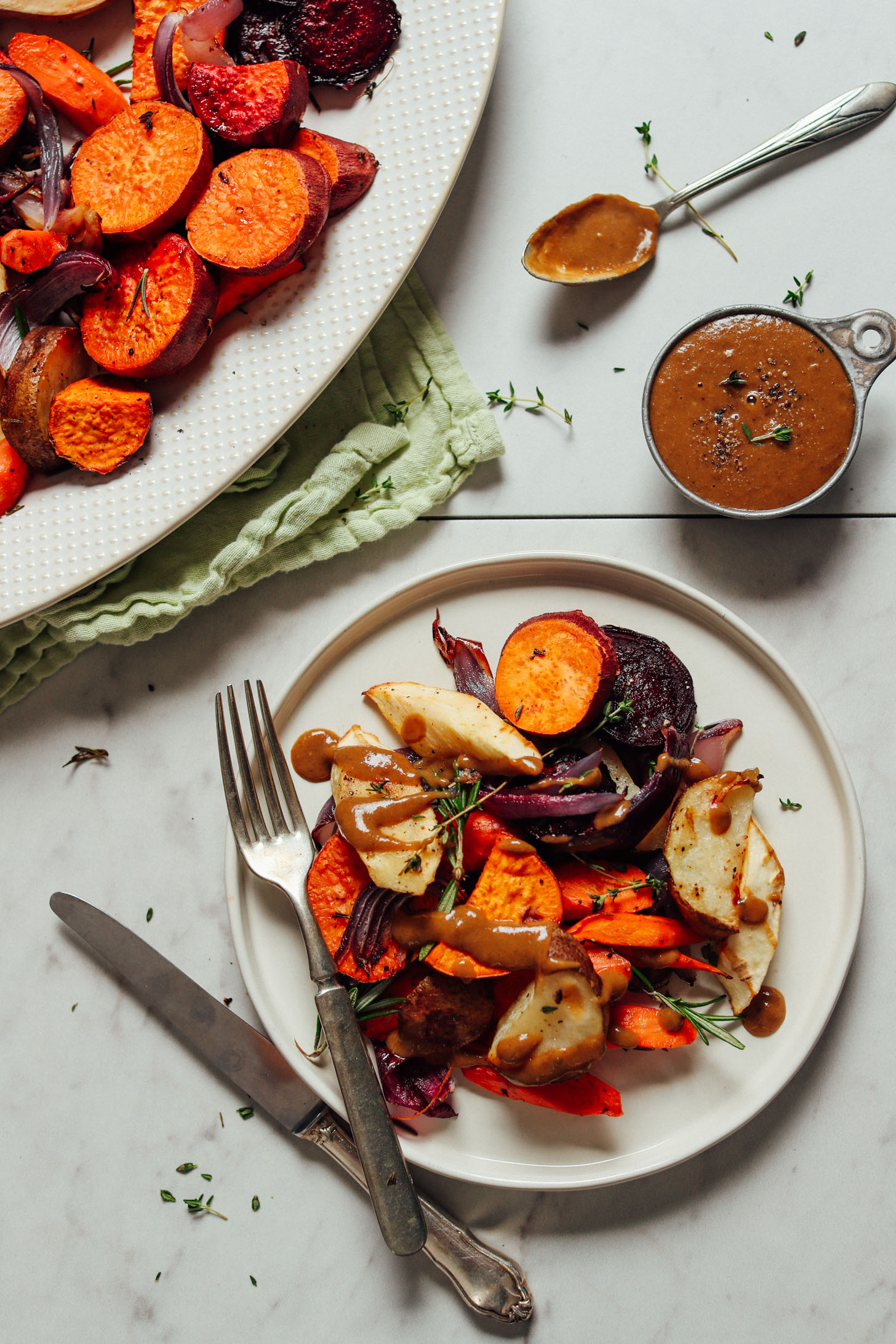 Plate and platter of Pan Roasted Vegetables with Fresh Herbs and a drizzle of vegan gravy