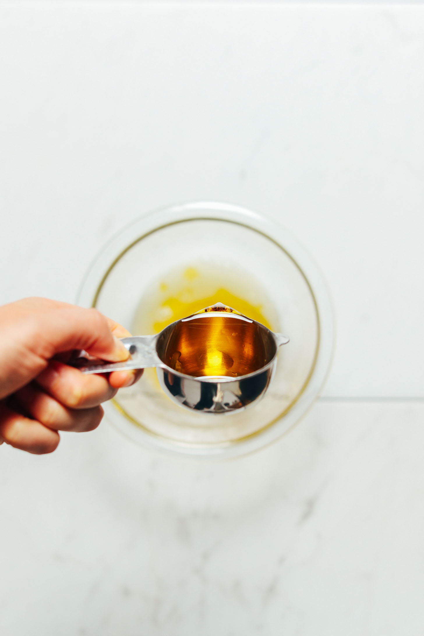 Pouring oil into a bowl for our tutorial on How to Make Lemon Vinaigrette
