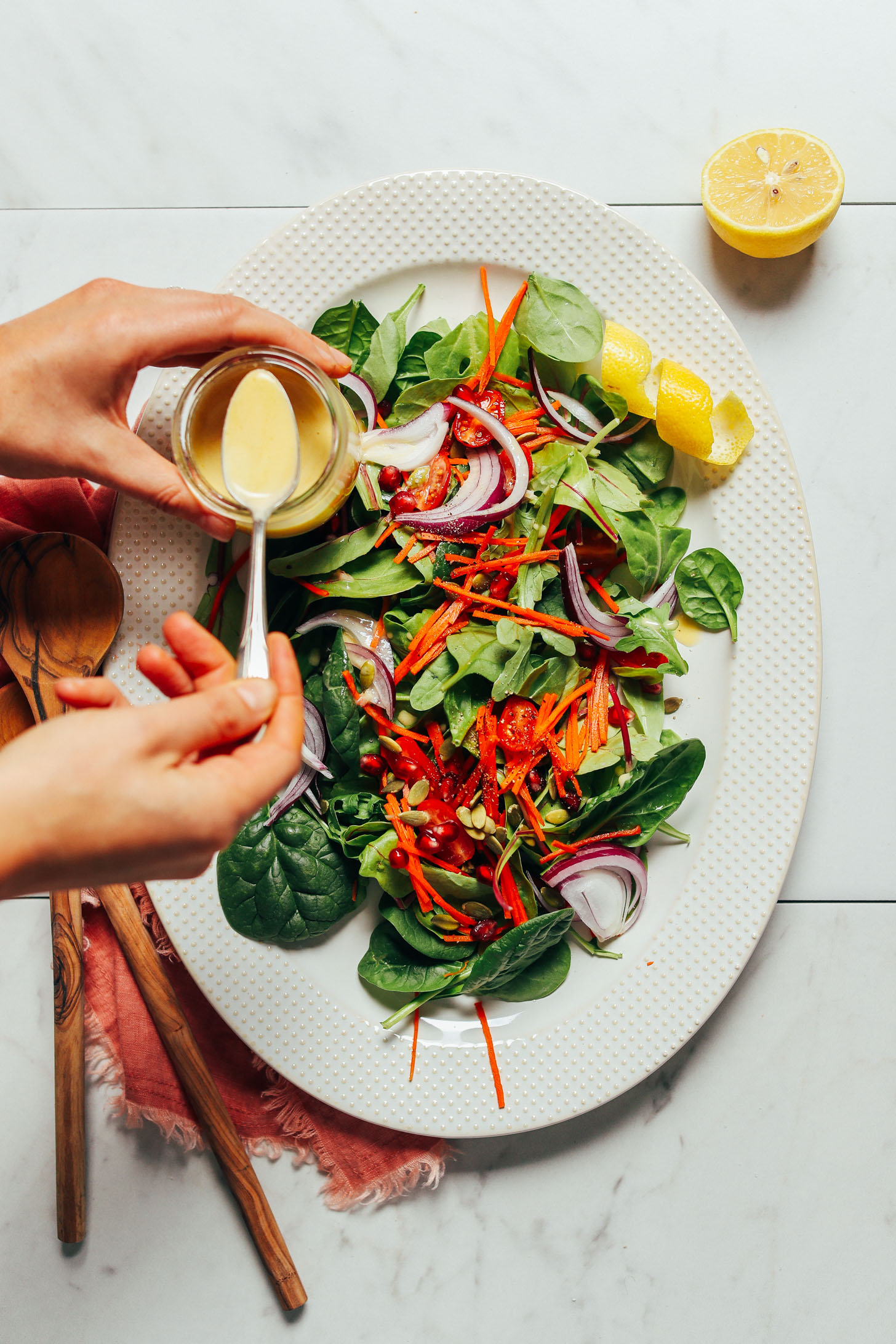 Using a spoon to drizzle dressing over a simple green salad