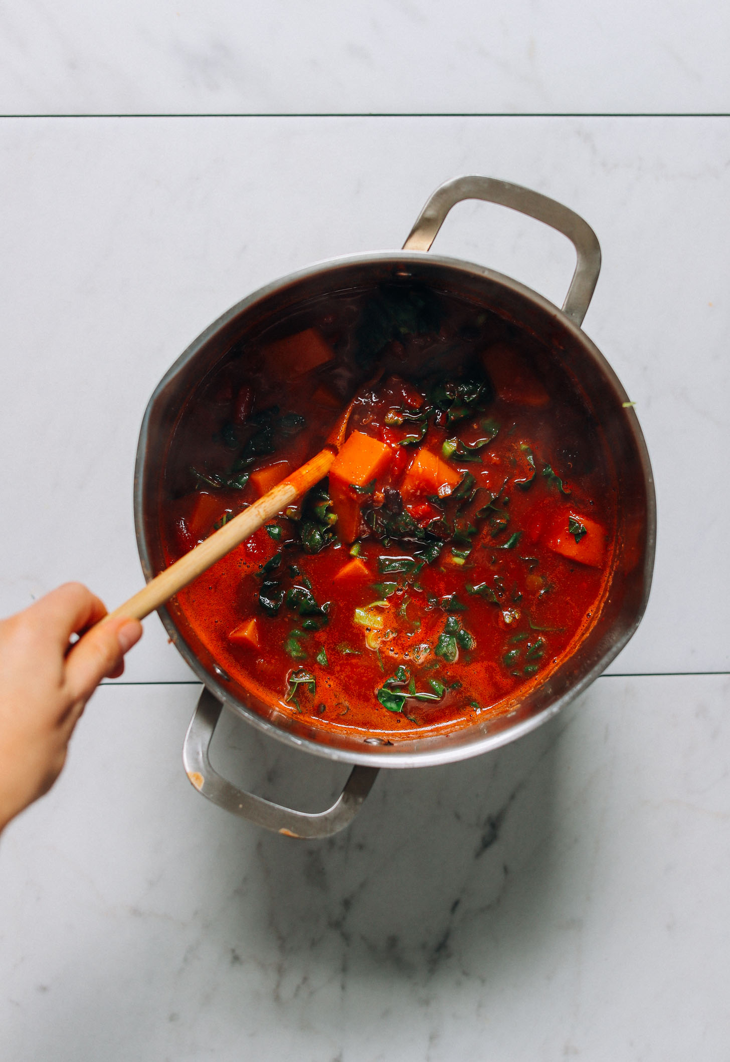 Stirring a pot of our hearty and flavorful Butternut Squash Quinoa chili recipe
