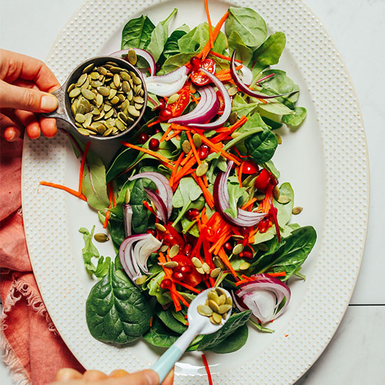Sprinkling pepitas for our Simple Green Salad recipe