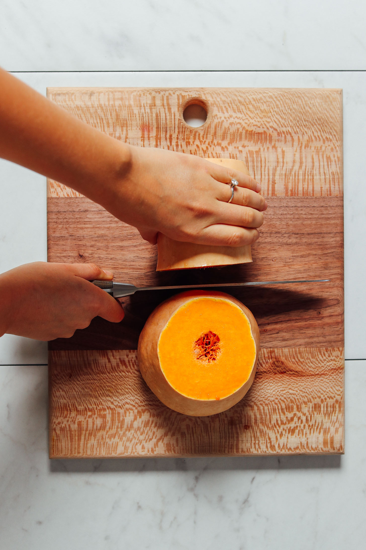 Butternut squash cut in half with the knife held between the two halves