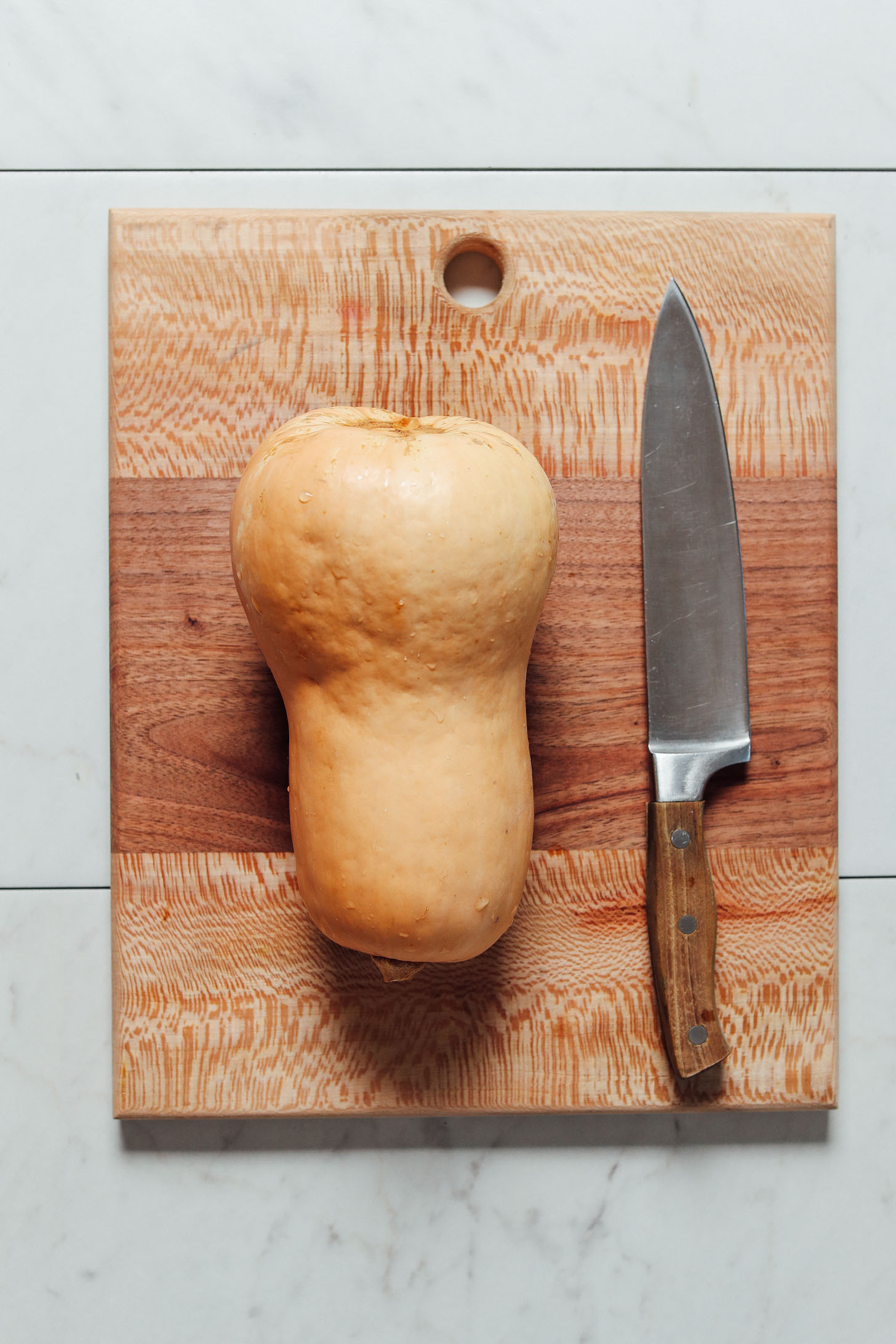 Photo of a knife and butternut squash on a cutting board for our How To Cut Butternut Squash Tutorial